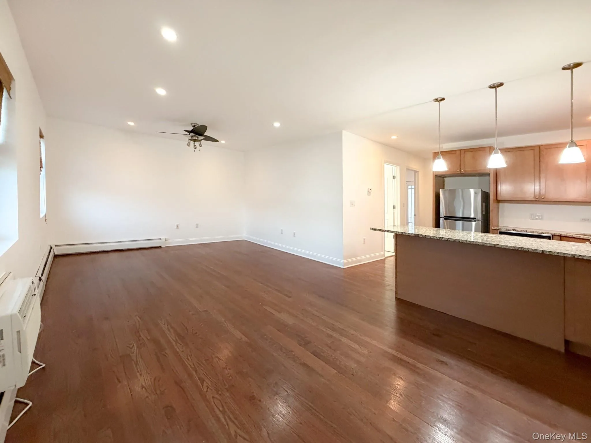 Unfurnished living room featuring recessed lighting, dark wood finished floors, ceiling fan, and an AC wall unit Unfurnished living room featuring recessed lighting, dark wood finished floors, ceiling fan, and an AC wall unit