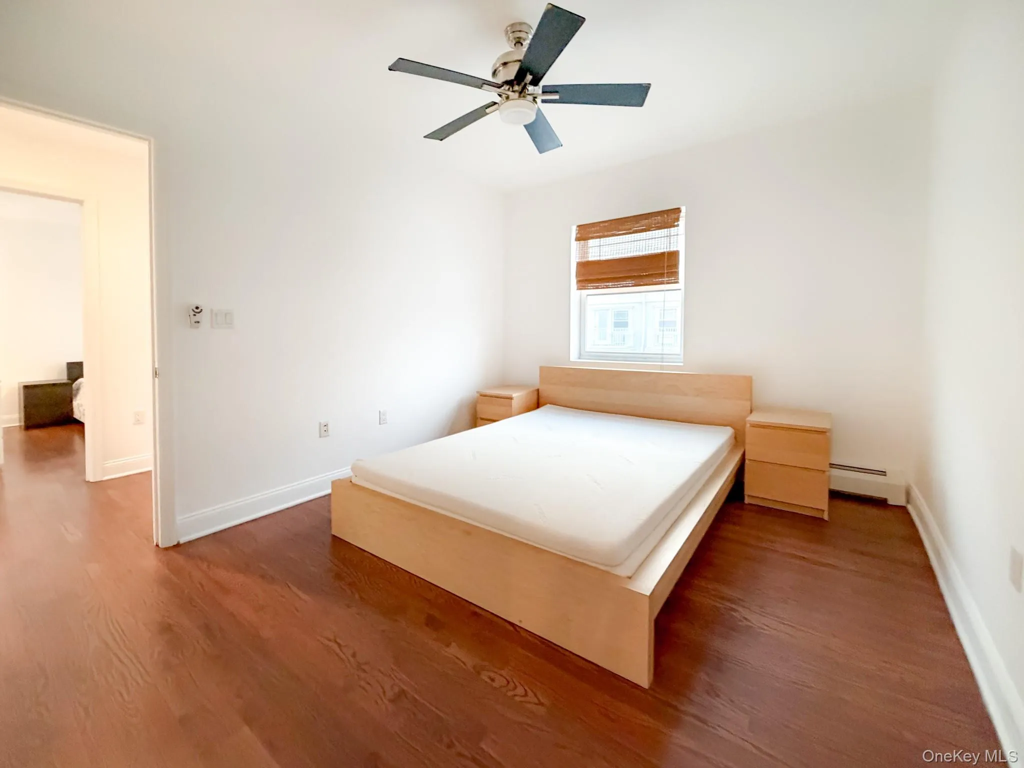 Bedroom with dark wood finished floors, a ceiling fan, and baseboard heating Bedroom with dark wood finished floors, a ceiling fan, and baseboard heating