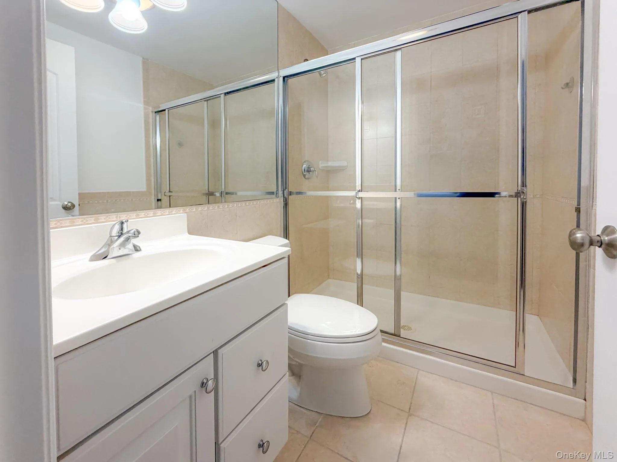 Full bathroom with vanity, a shower stall, and light tile patterned floors Full bathroom with vanity, a shower stall, and light tile patterned floors
