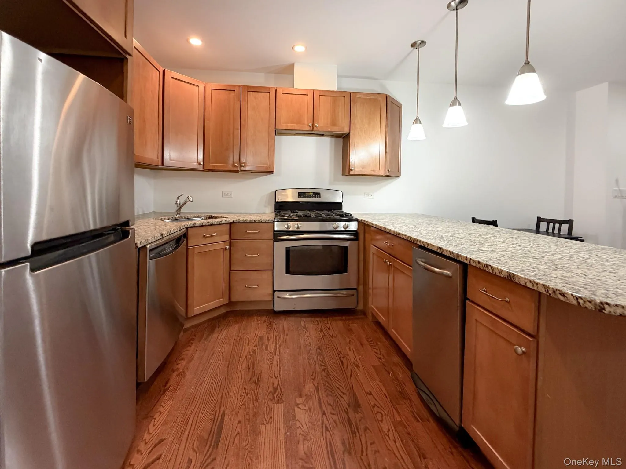 Kitchen featuring stainless steel appliances, light stone countertops, pendant lighting, a peninsula, and recessed lighting Kitchen featuring stainless steel appliances, light stone countertops, pendant lighting, a peninsula, and recessed lighting