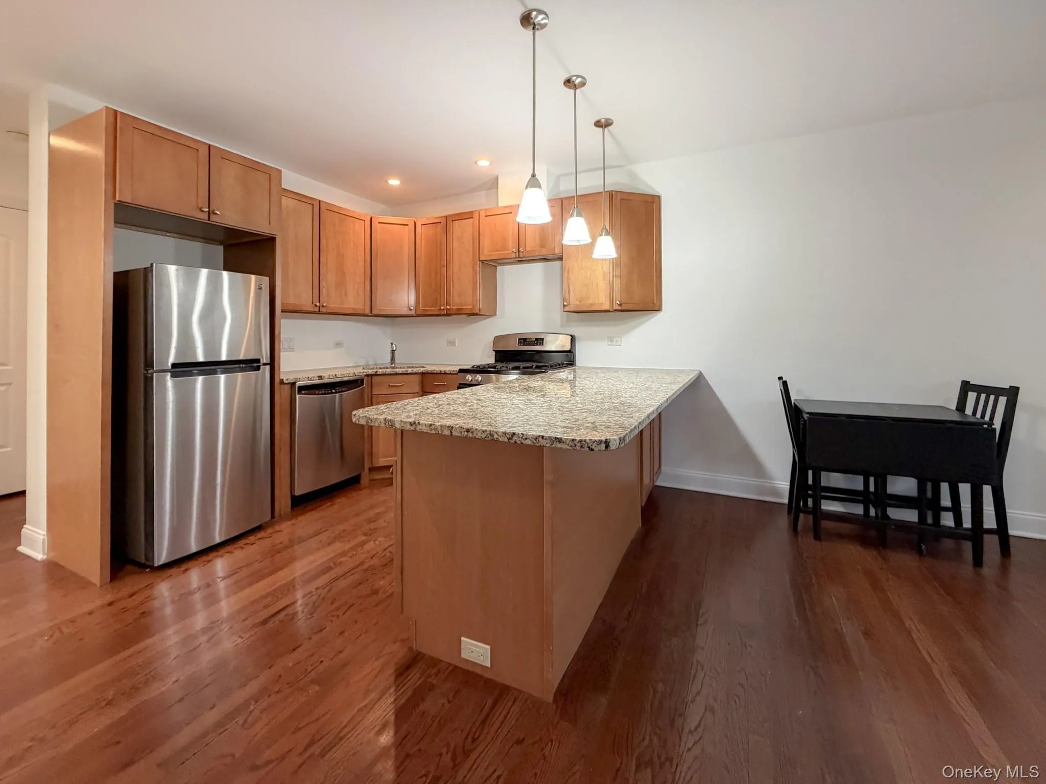 Kitchen with a peninsula, stainless steel appliances, pendant lighting, light stone countertops, and recessed lighting Kitchen with a peninsula, stainless steel appliances, pendant lighting, light stone countertops, and recessed lighting