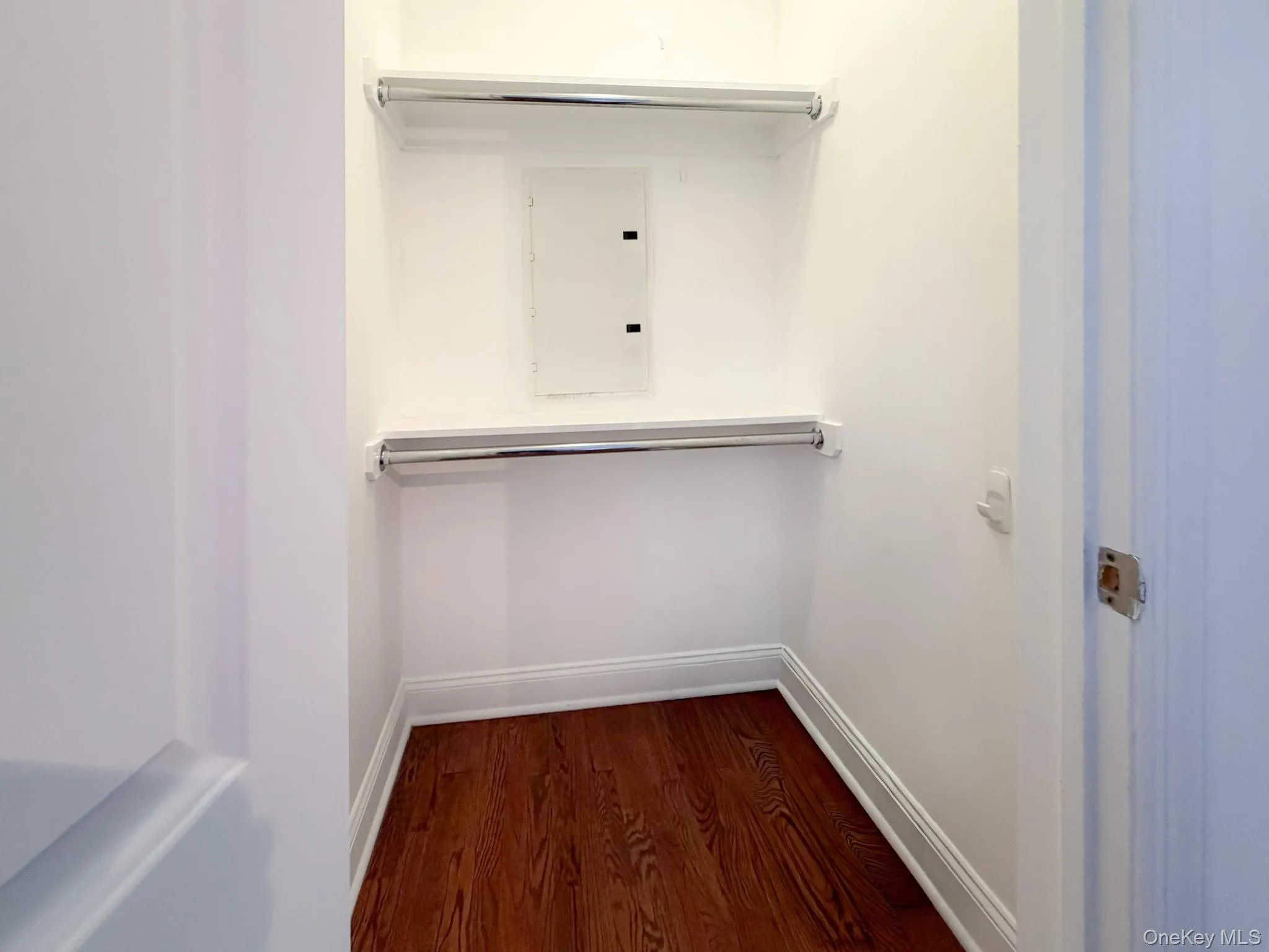 Walk in closet featuring electric panel and dark wood-style flooring Walk in closet featuring electric panel and dark wood-style flooring