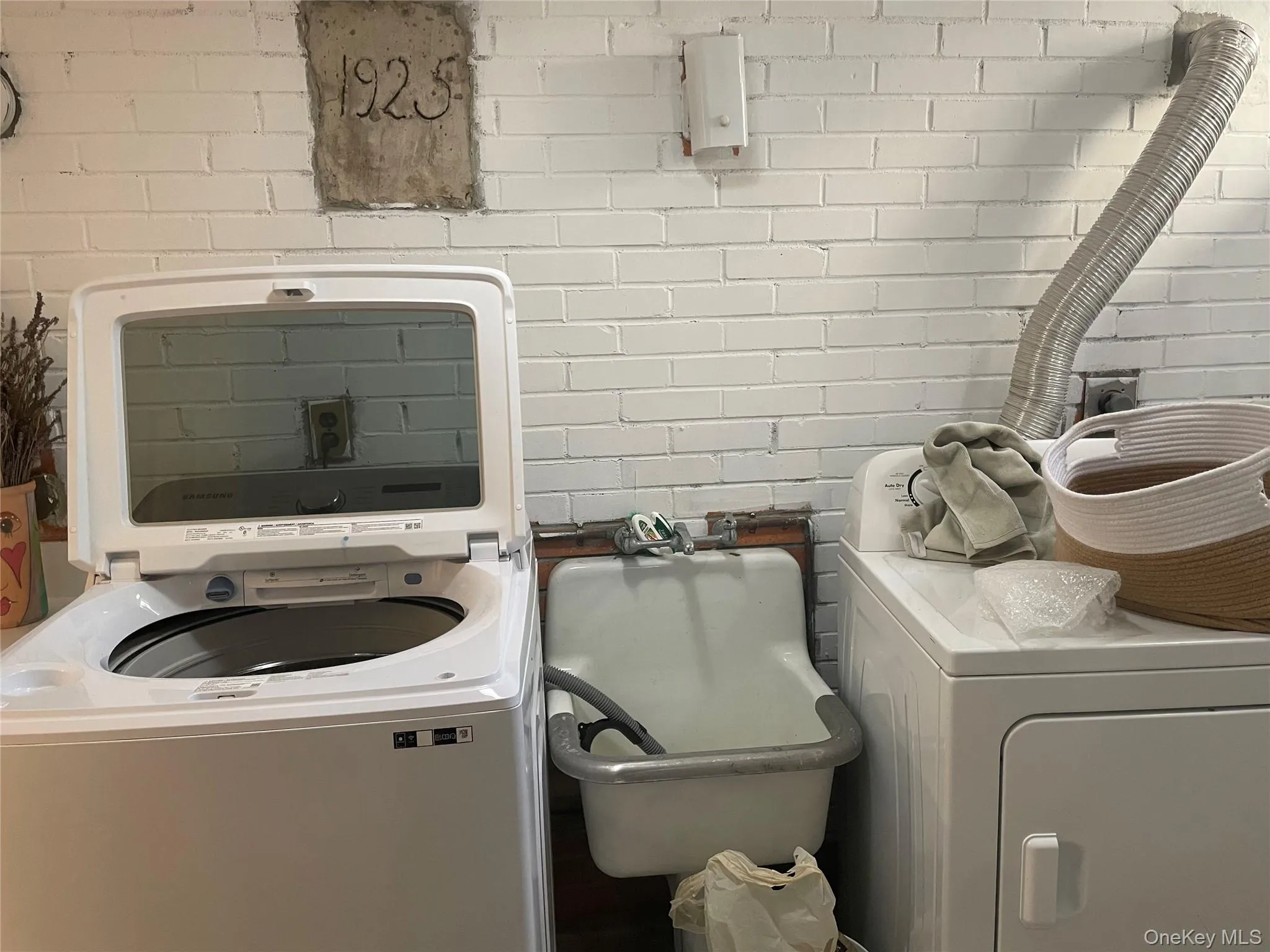 Laundry room with washer / dryer and brick wall Laundry room with washer / dryer and brick wall