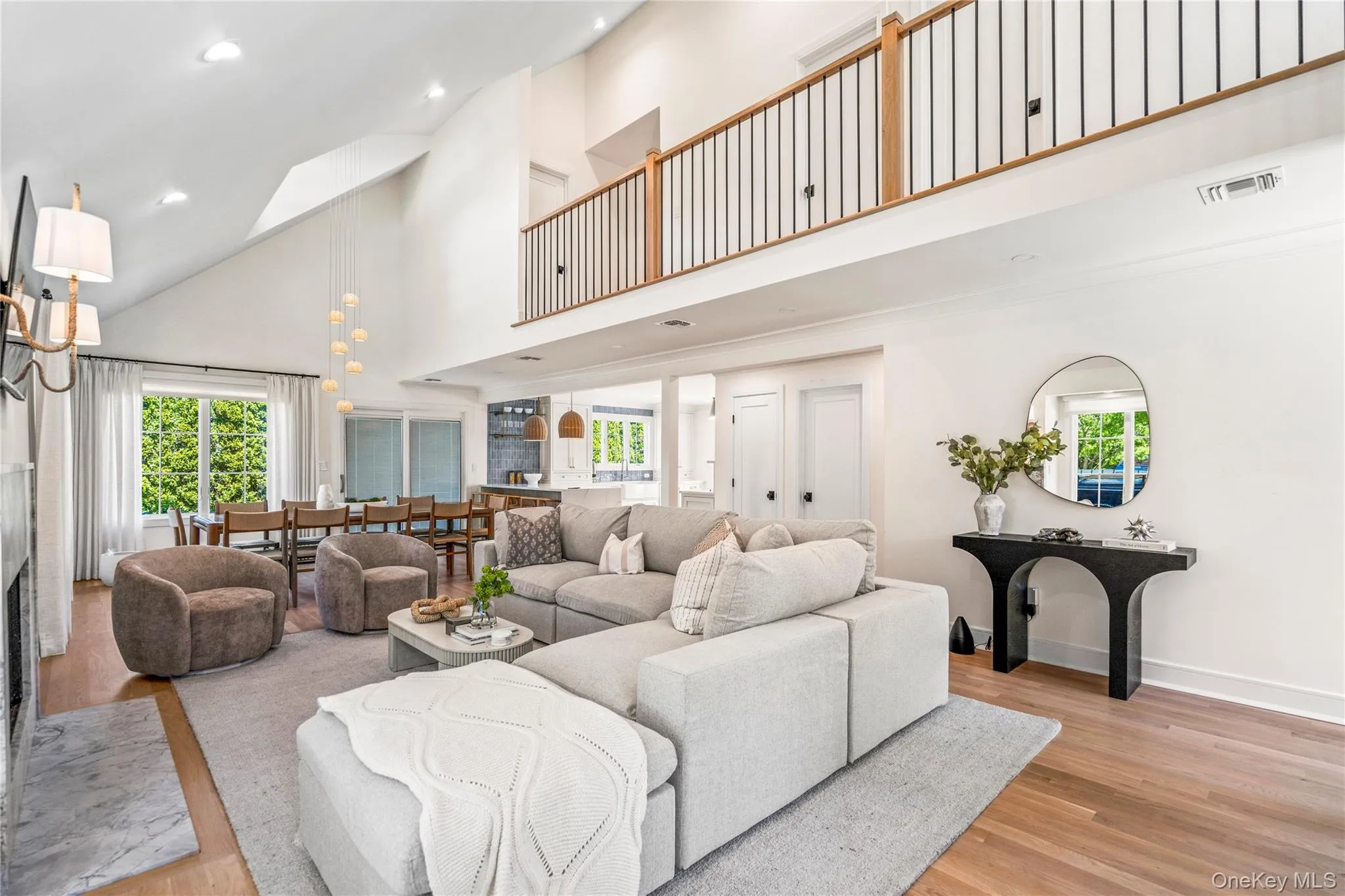 Living area with a fireplace, a towering ceiling, light wood-type flooring, recessed lighting, and healthy amount of natural light Living area with a fireplace, a towering ceiling, light wood-type flooring, recessed lighting, and healthy amount of natural light
