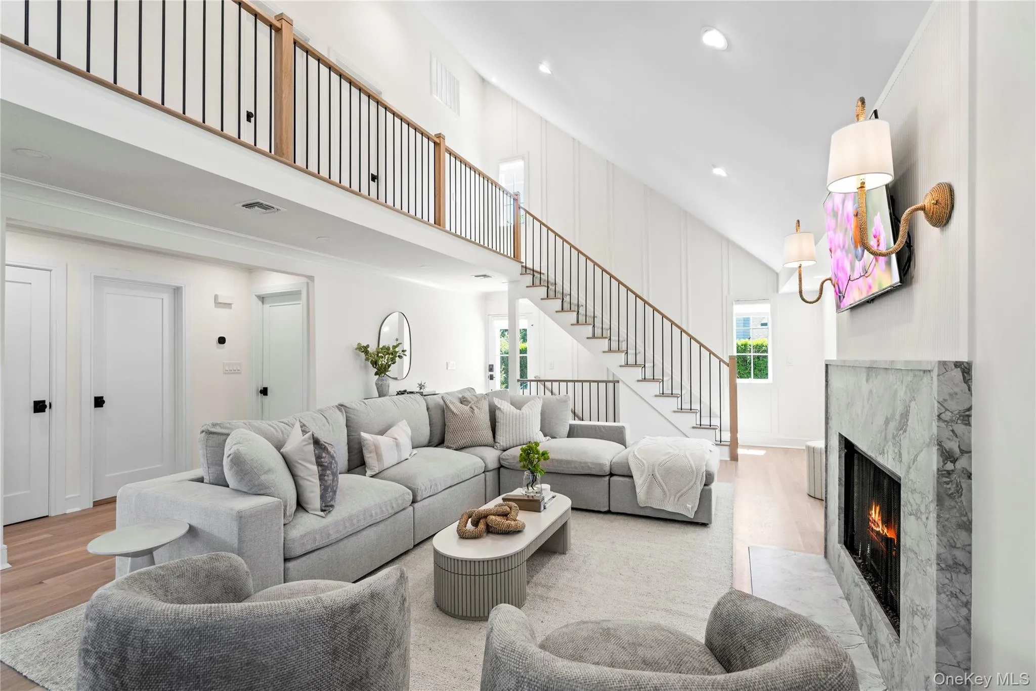 Living room featuring a fireplace, stairway, recessed lighting, wood finished floors, and a towering ceiling Living room featuring a fireplace, stairway, recessed lighting, wood finished floors, and a towering ceiling