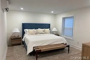 Bedroom with a wall unit AC, recessed lighting, and wood finished floors Bedroom with a wall unit AC, recessed lighting, and wood finished floors