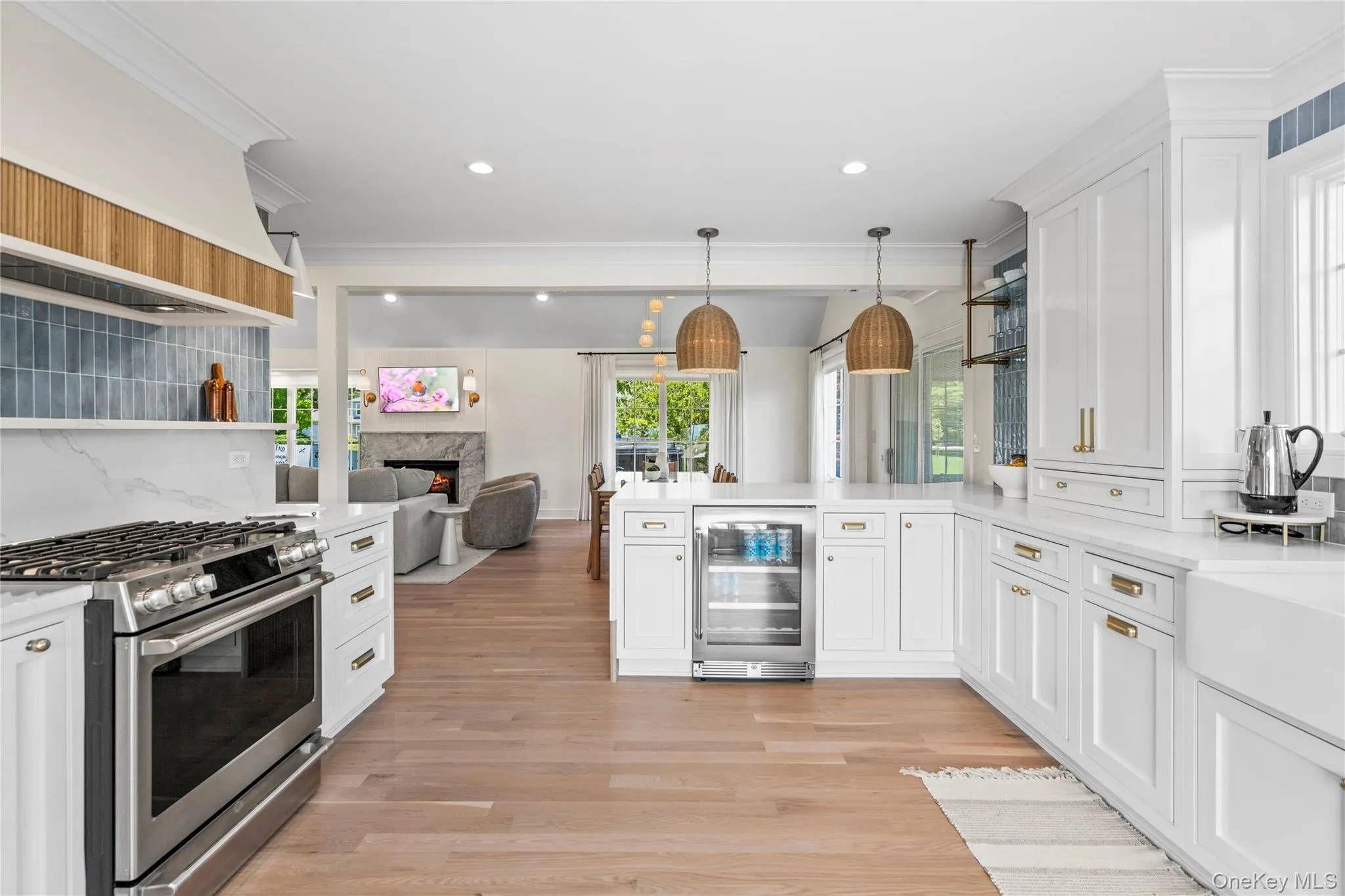 Kitchen with stainless steel gas stove, open shelves, open floor plan, wine cooler, and white cabinetry Kitchen with stainless steel gas stove, open shelves, open floor plan, wine cooler, and white cabinetry