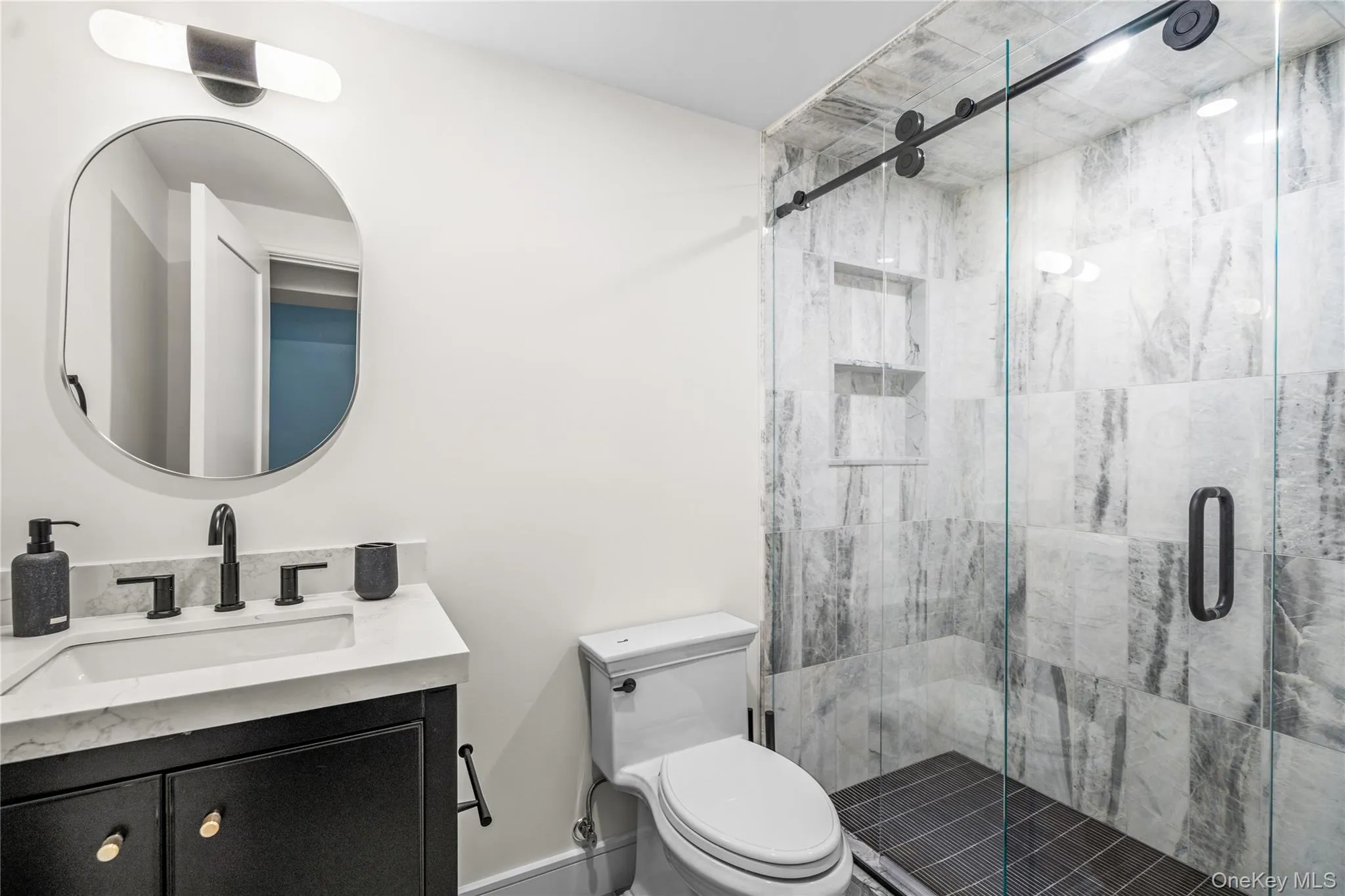 Full bath featuring vanity and a marble finish shower Full bath featuring vanity and a marble finish shower