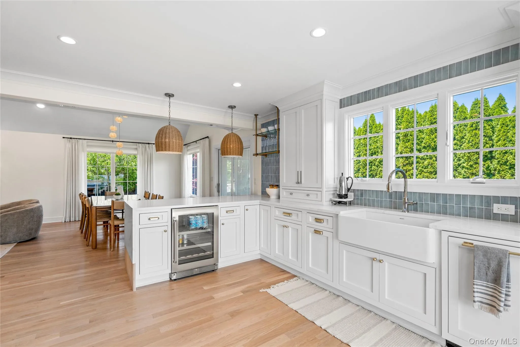 Kitchen featuring a peninsula, decorative light fixtures, white cabinetry, beverage cooler, and light stone counters Kitchen featuring a peninsula, decorative light fixtures, white cabinetry, beverage cooler, and light stone counters