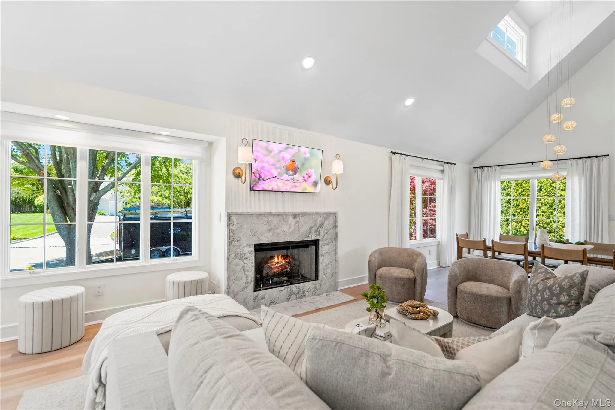 Living area with healthy amount of natural light, high vaulted ceiling, a high end fireplace, wood finished floors, and recessed lighting Living area with healthy amount of natural light, high vaulted ceiling, a high end fireplace, wood finished floors, and recessed lighting