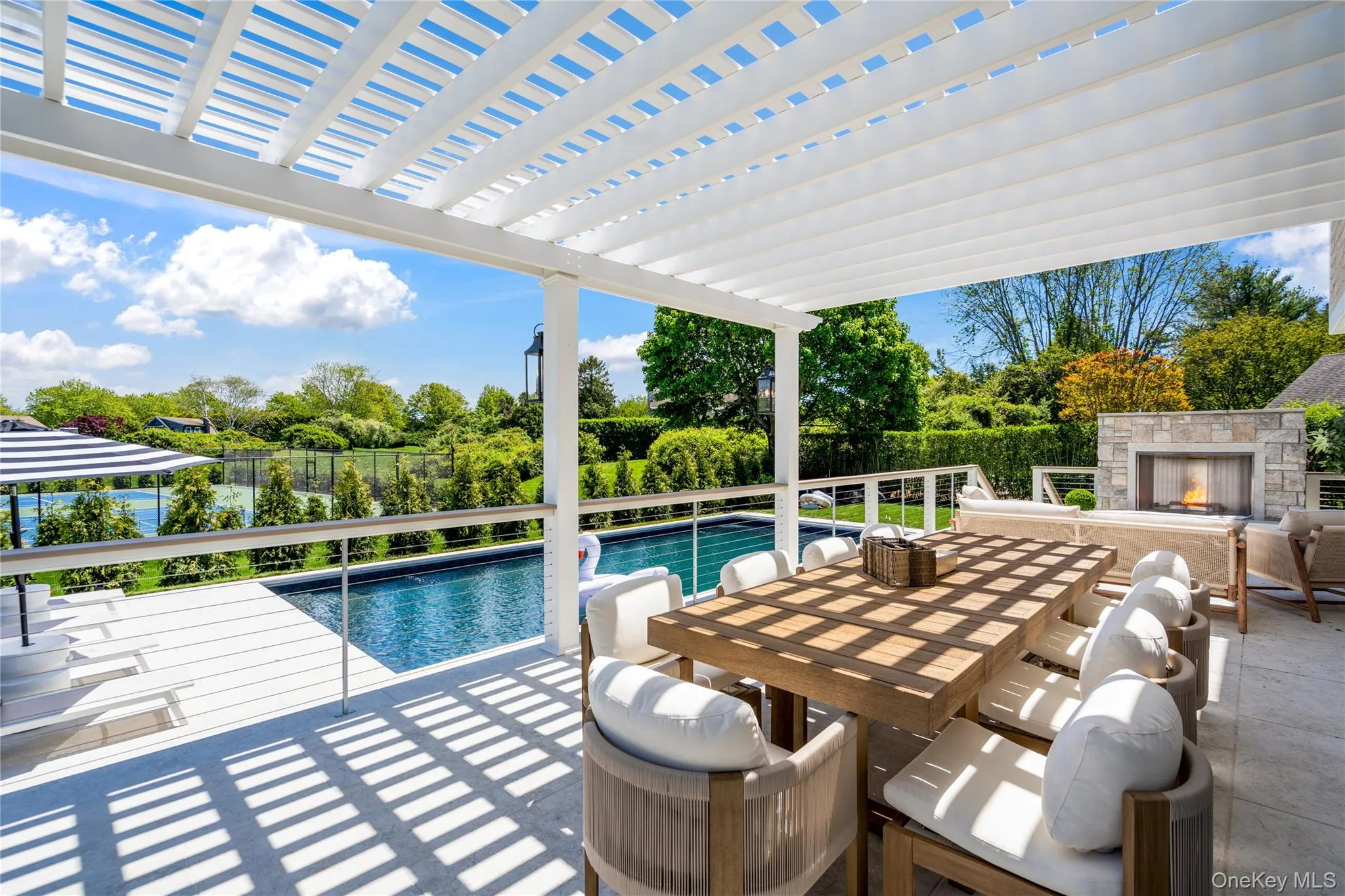 View of swimming pool featuring an outdoor stone fireplace, outdoor dining space, a pergola, and a patio View of swimming pool featuring an outdoor stone fireplace, outdoor dining space, a pergola, and a patio