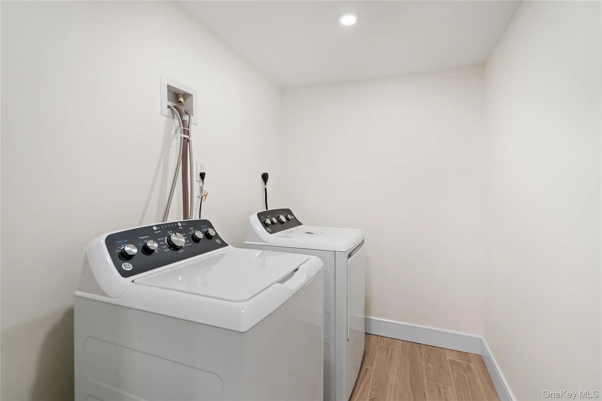 Laundry area featuring light wood-style flooring, washing machine and dryer, and recessed lighting Laundry area featuring light wood-style flooring, washing machine and dryer, and recessed lighting