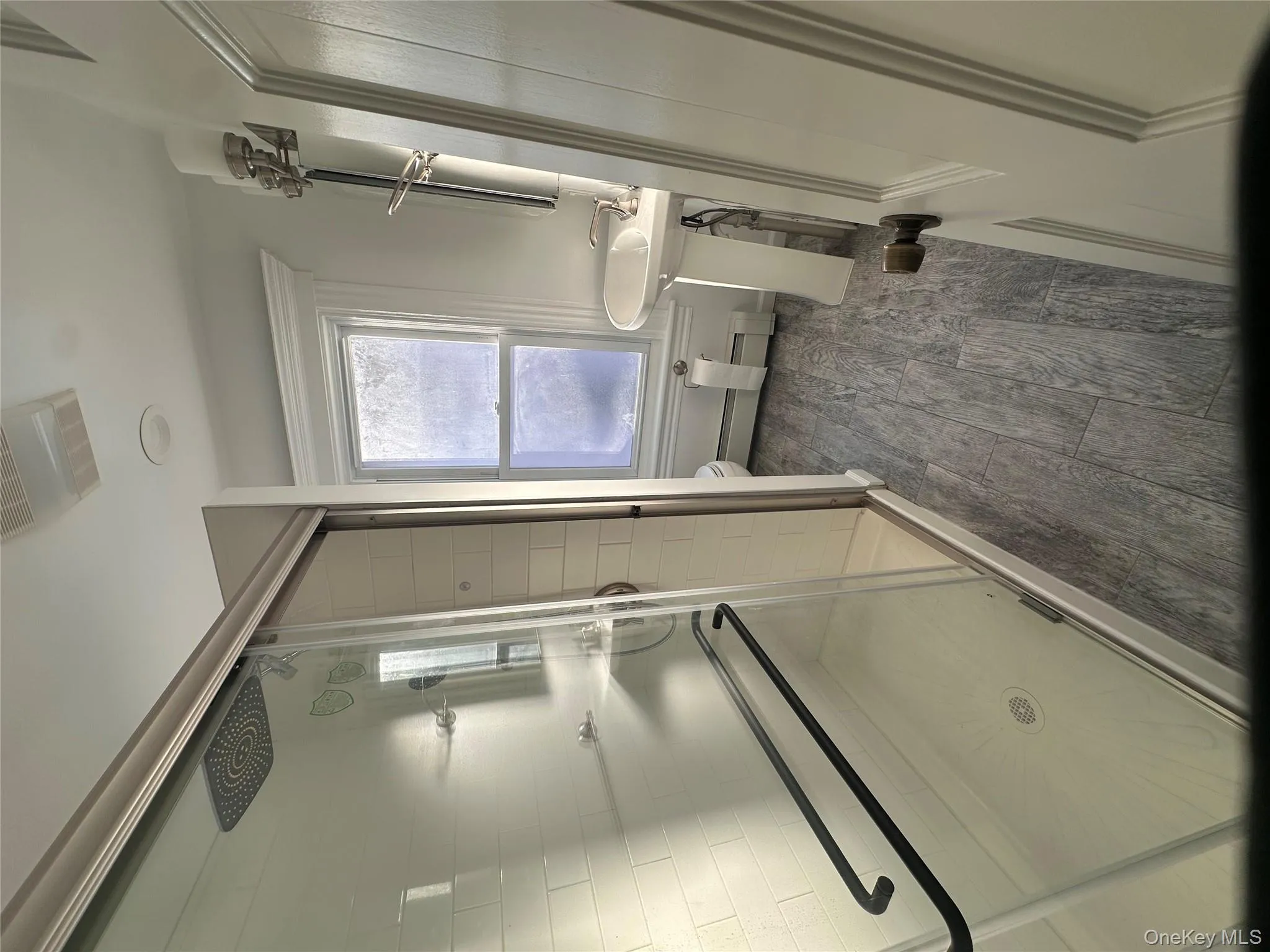 Full bathroom with a stall shower, wood finish floors, and a baseboard heating unit Full bathroom with a stall shower, wood finish floors, and a baseboard heating unit