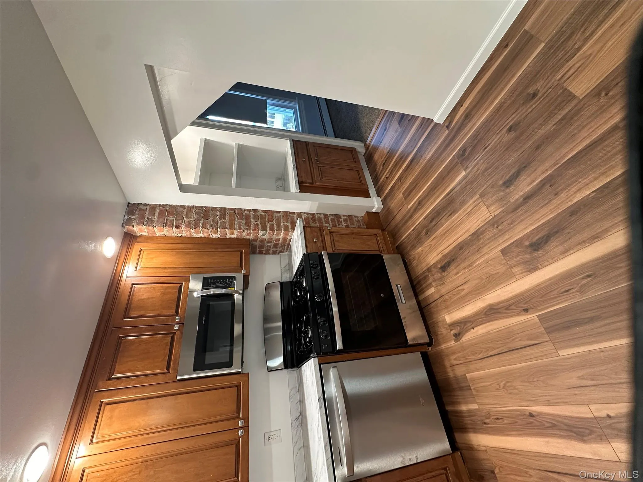 Kitchen featuring appliances with stainless steel finishes, brown cabinetry, and dark wood-style flooring Kitchen featuring appliances with stainless steel finishes, brown cabinetry, and dark wood-style flooring