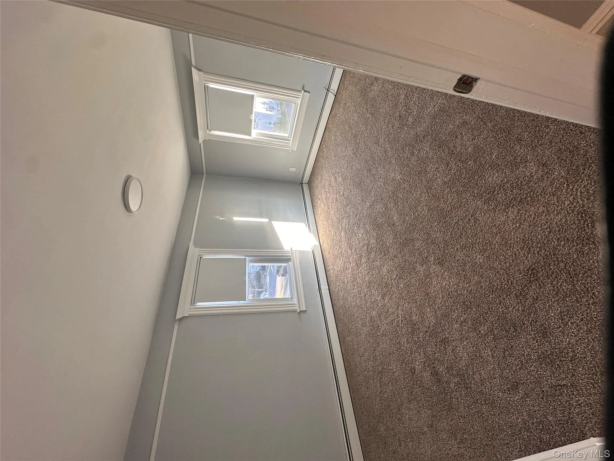 Unfurnished bedroom featuring carpet flooring, multiple windows, and a baseboard heating unit Unfurnished bedroom featuring carpet flooring, multiple windows, and a baseboard heating unit