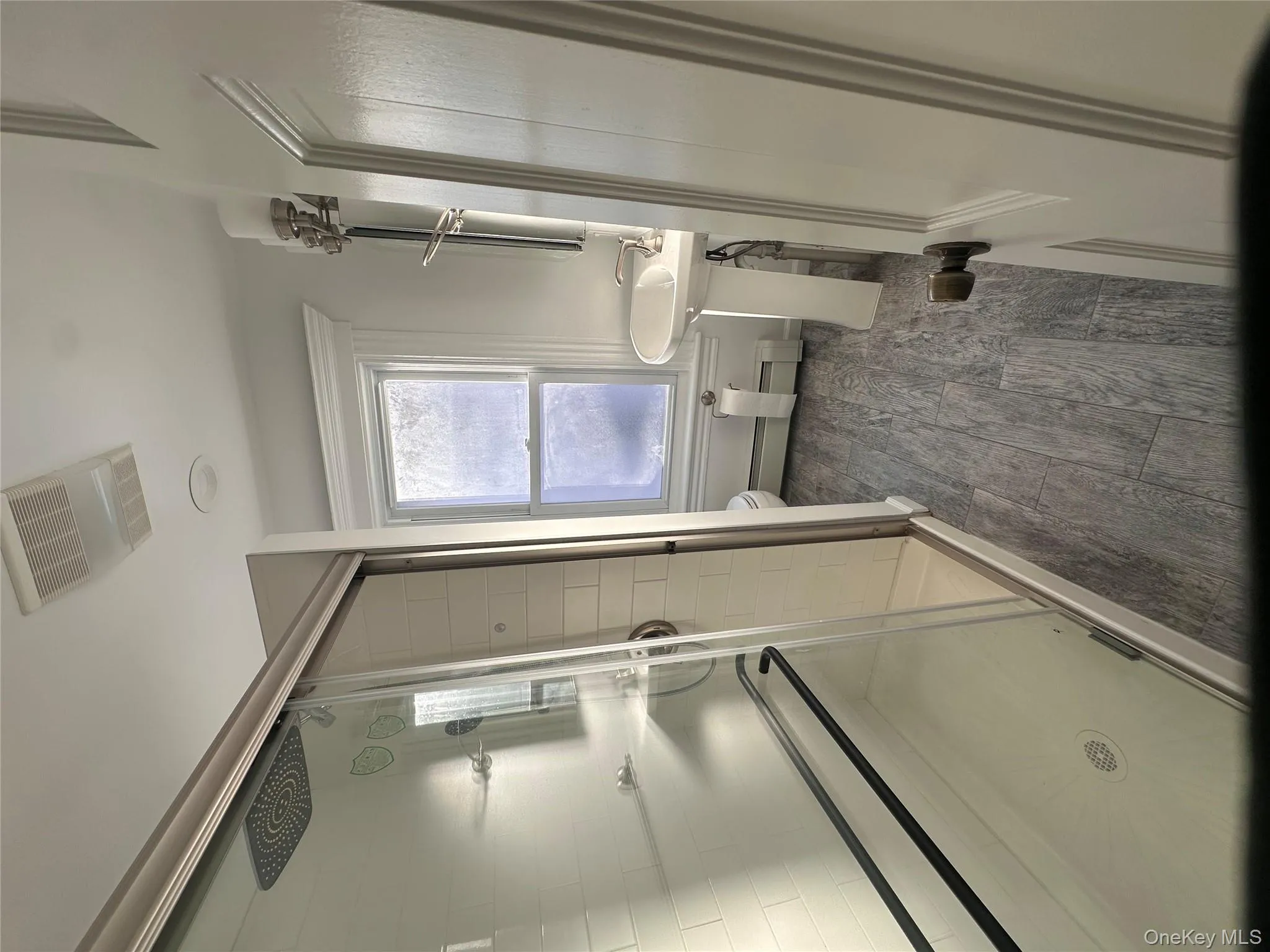 Bathroom featuring a shower stall, wood tiled floors, and baseboard heating Bathroom featuring a shower stall, wood tiled floors, and baseboard heating