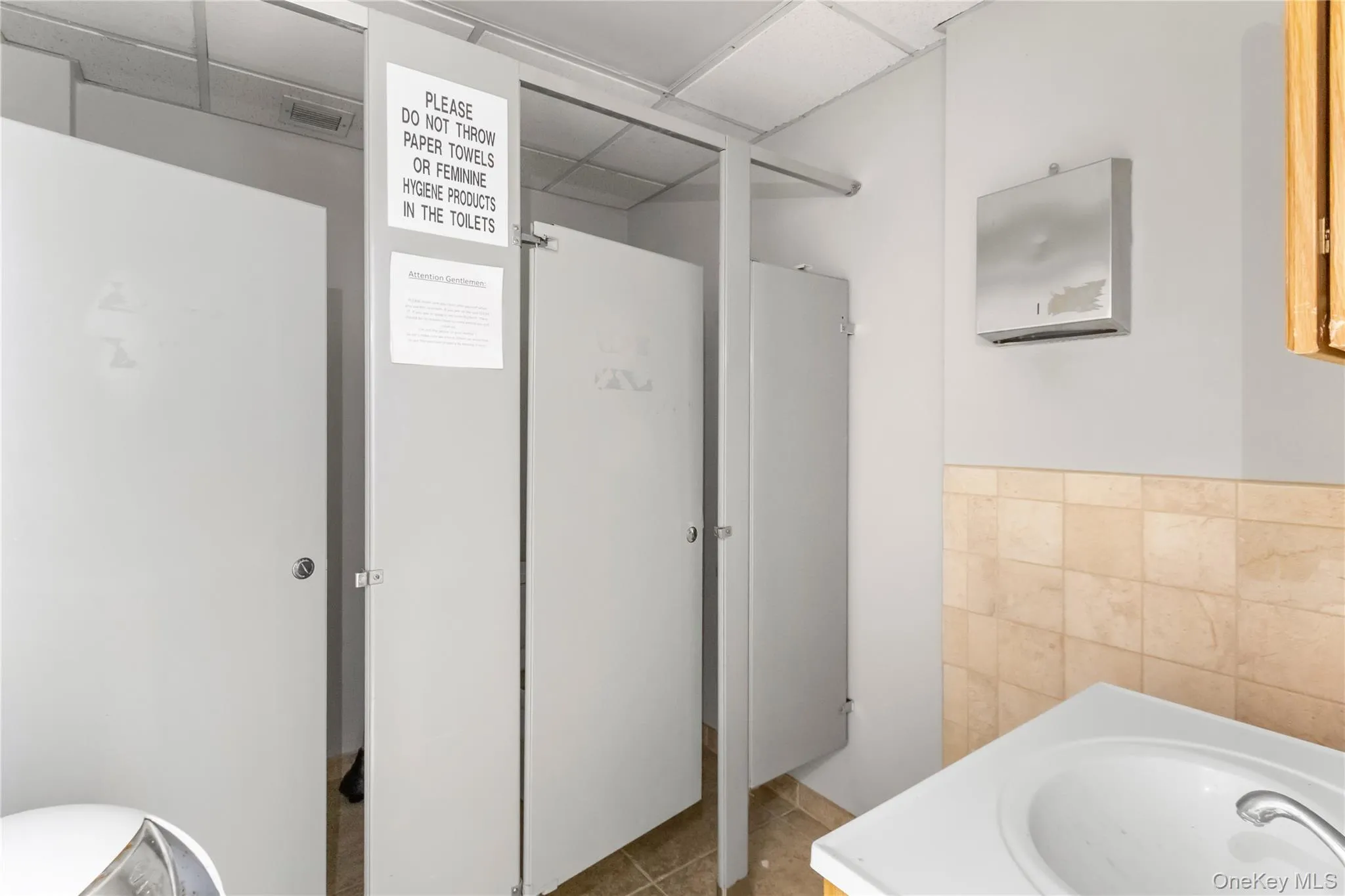 Bathroom with vanity, tile walls, a paneled ceiling, and a wainscoted wall Bathroom with vanity, tile walls, a paneled ceiling, and a wainscoted wall