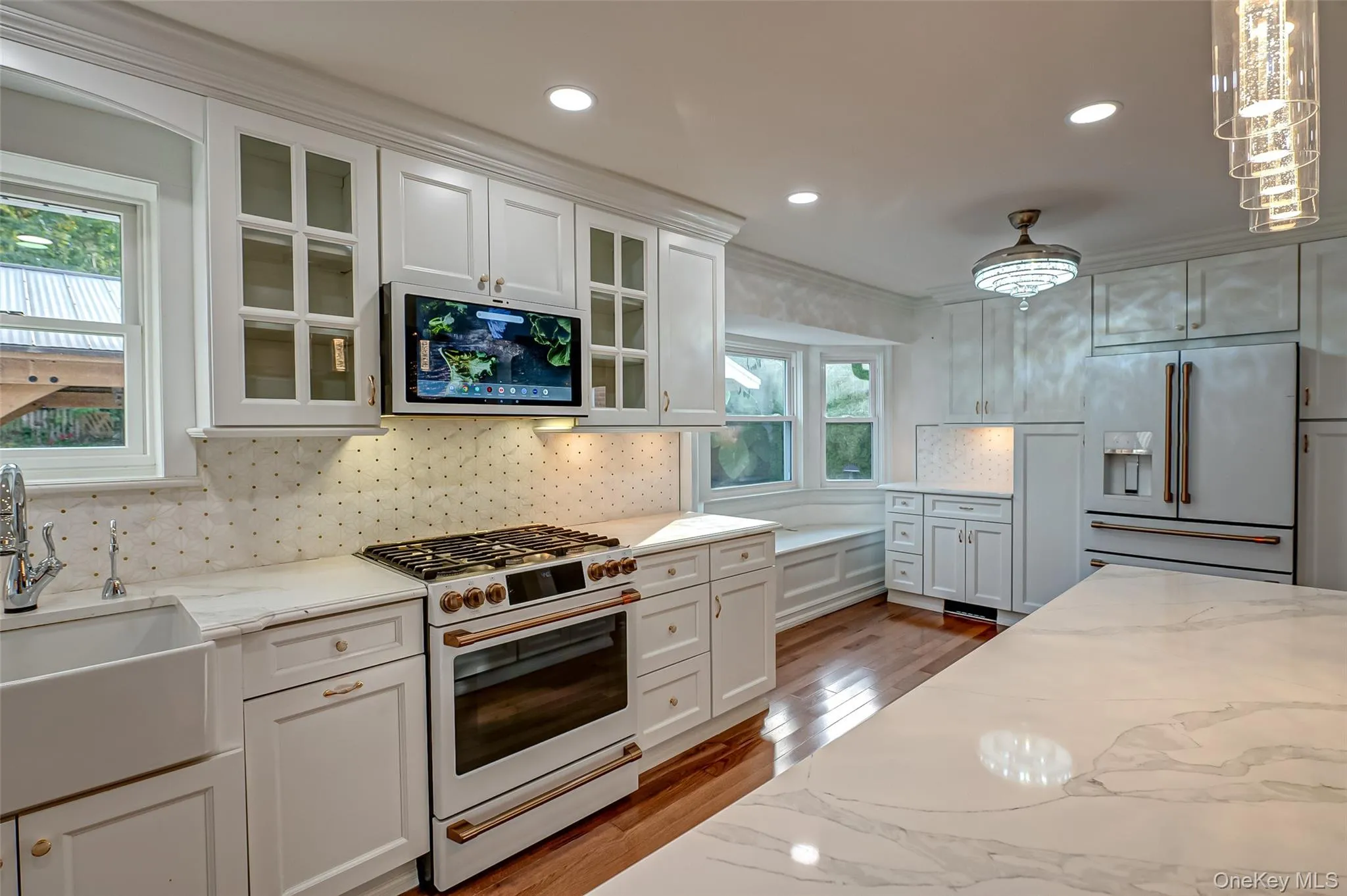 Kitchen featuring GE cafe white appliances, white cabinetry, light marble countertops, recessed lighting, and crown molding Kitchen featuring GE cafe white appliances, white cabinetry, light marble countertops, recessed lighting, and crown molding