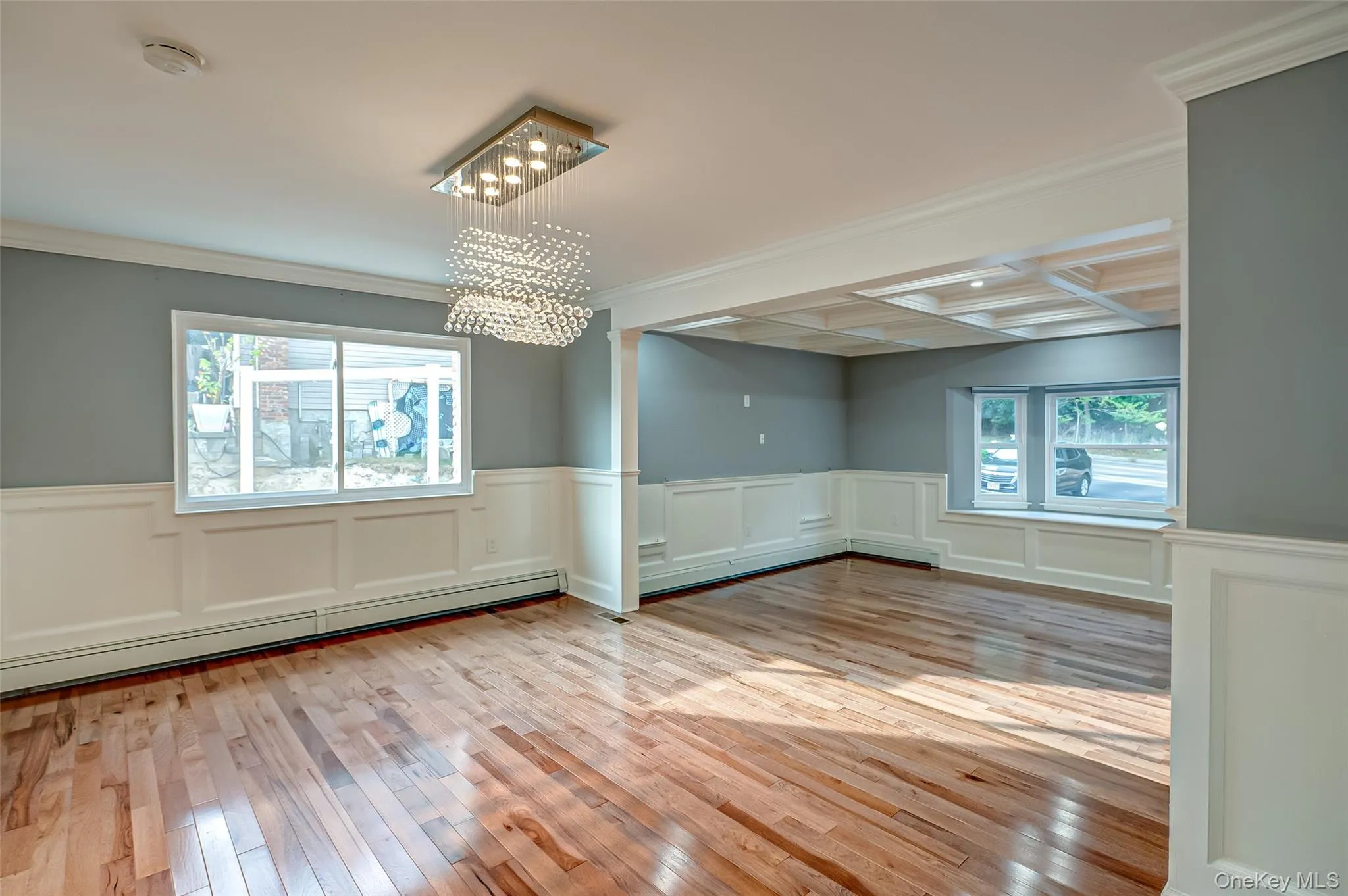 living room then dining area, picture frame molding, wood flooring, crown molding, and coffered ceiling living room then dining area, picture frame molding, wood flooring, crown molding, and coffered ceiling