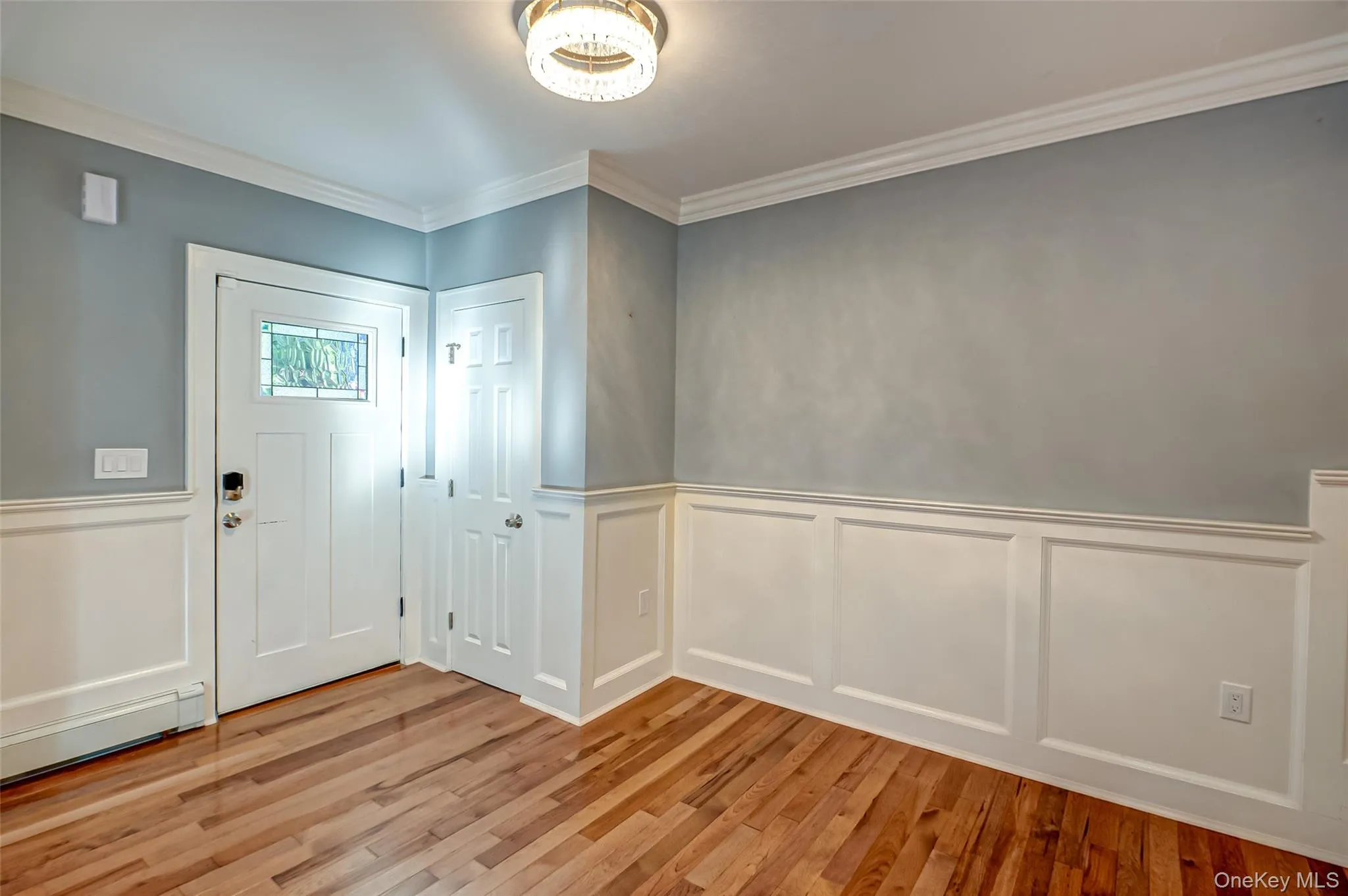 Foyer entrance with wainscoting, a decorative wall, light wood finished floors, and ornamental molding Foyer entrance with wainscoting, a decorative wall, light wood finished floors, and ornamental molding