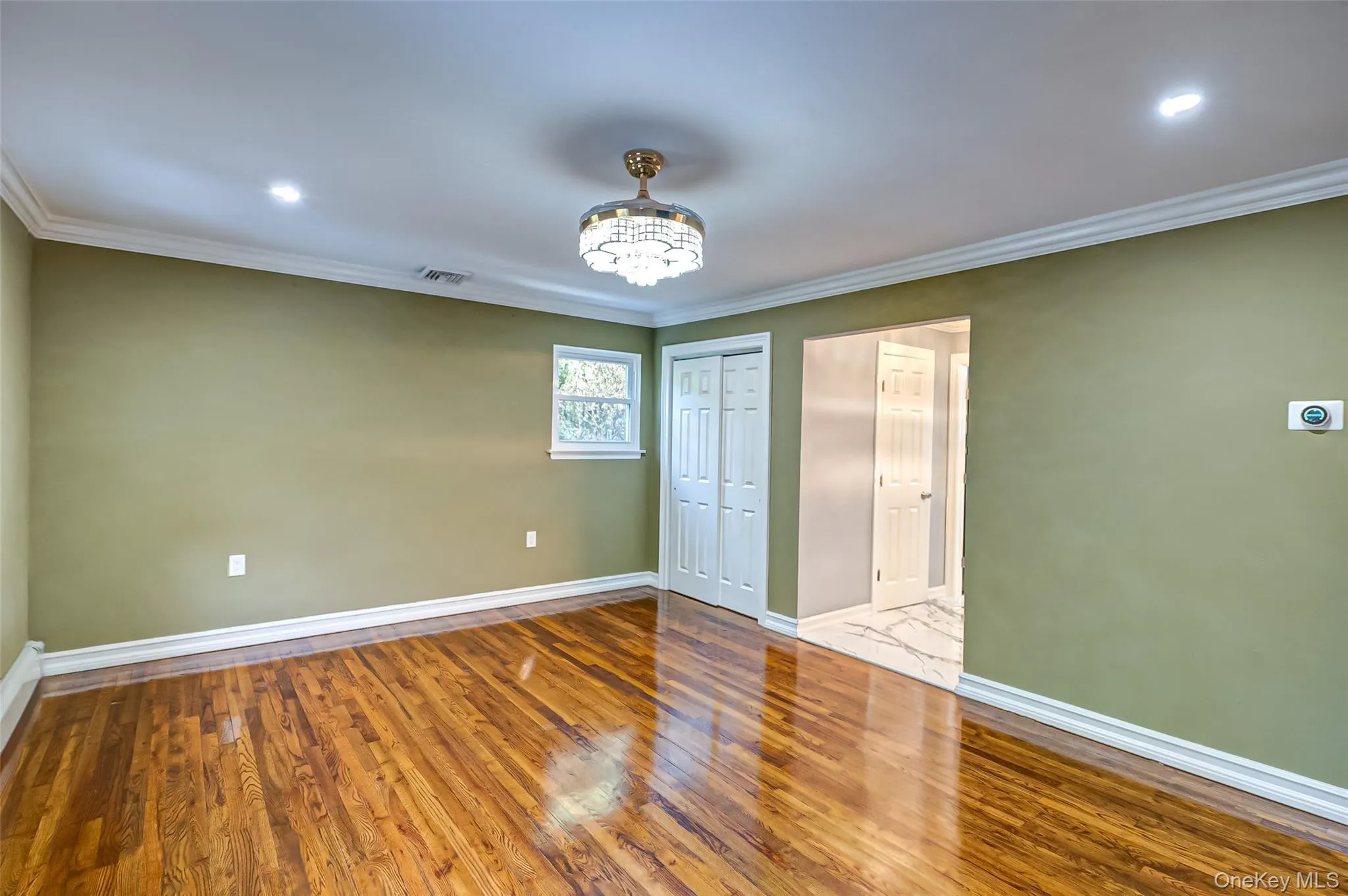 primary bedroom featuring hardwood wood floors, a chandelier, recessed lighting, crown molding, and a closet and ensuite bathroom primary bedroom featuring hardwood wood floors, a chandelier, recessed lighting, crown molding, and a closet and ensuite bathroom