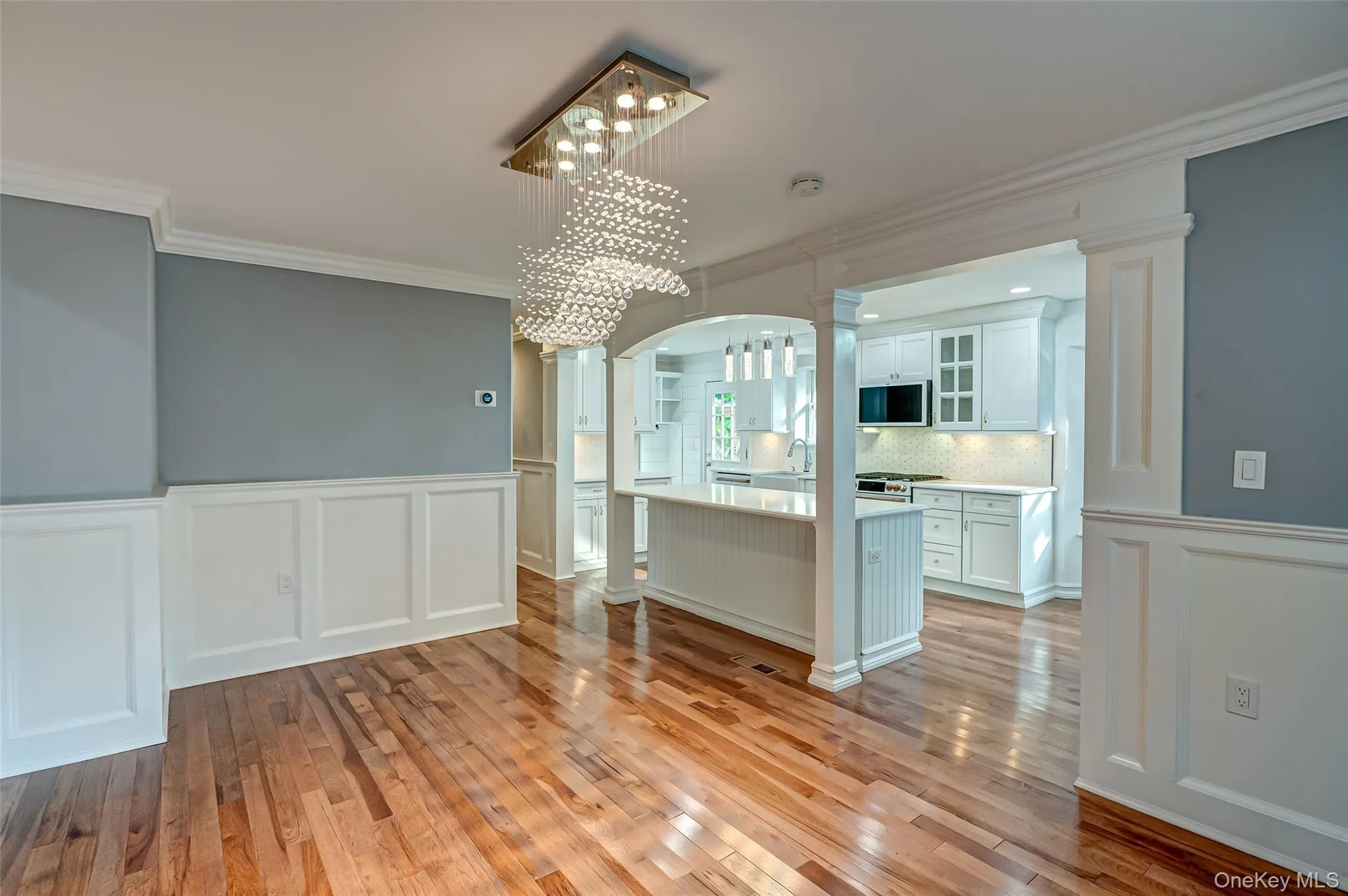 dining area flows into kitchen and breakfast bar, wood floors, and ornate columns dining area flows into kitchen and breakfast bar, wood floors, and ornate columns