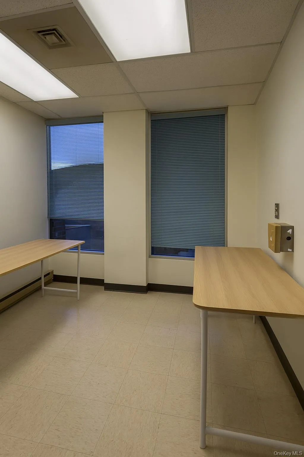 Misc room with a drop ceiling, baseboard heating, and light flooring Misc room with a drop ceiling, baseboard heating, and light flooring