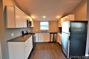 Kitchen featuring stainless steel appliances, dark wood-type flooring, white cabinets, vaulted ceiling, and recessed lighting Kitchen featuring stainless steel appliances, dark wood-type flooring, white cabinets, vaulted ceiling, and recessed lighting
