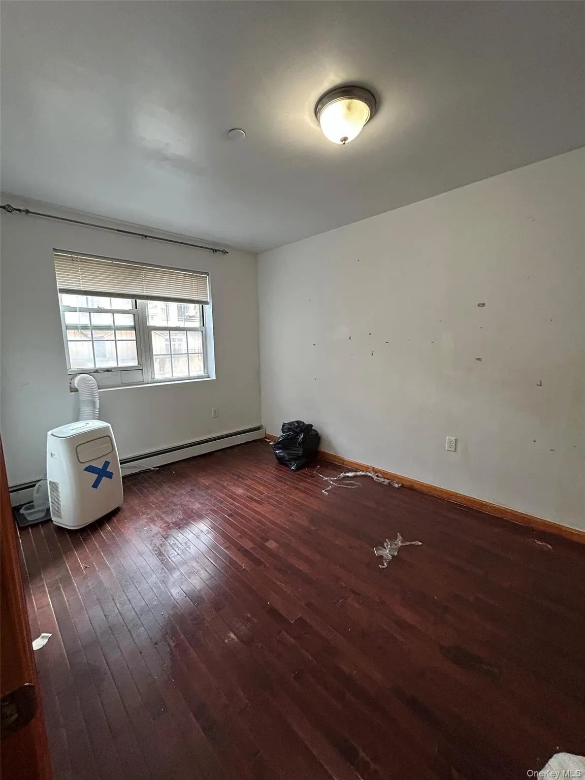 Spare room with dark wood-style flooring and a baseboard heating unit Spare room with dark wood-style flooring and a baseboard heating unit