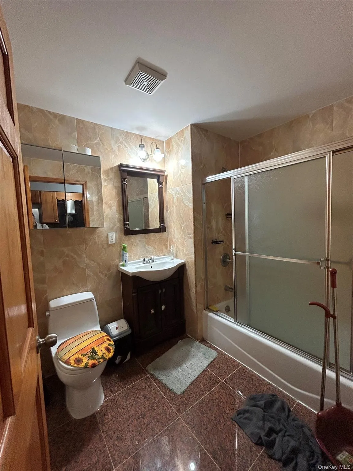 Bathroom featuring shower / bath combination with glass door, tile walls, and vanity Bathroom featuring shower / bath combination with glass door, tile walls, and vanity