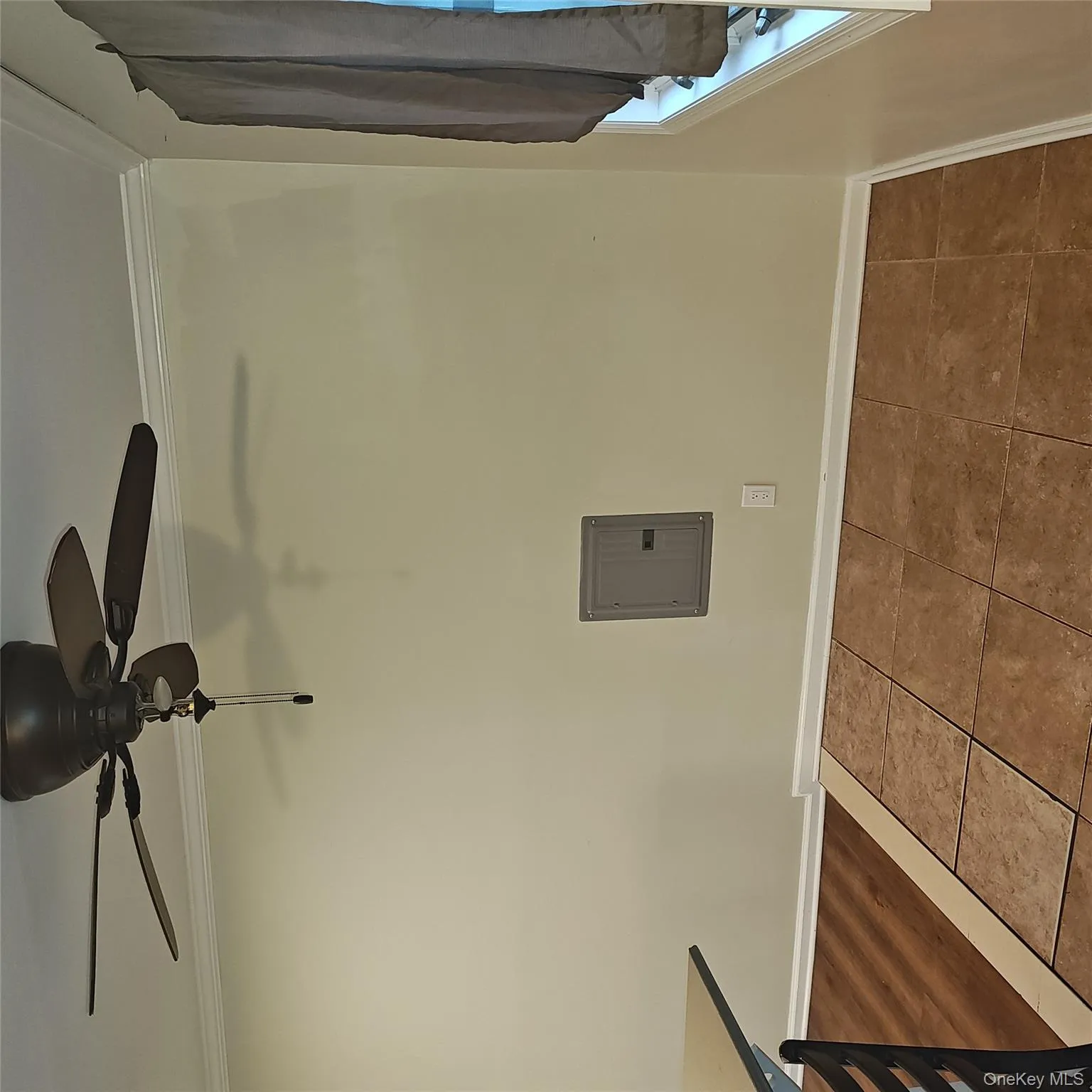 Tiled empty room featuring crown molding, electric panel, and a ceiling fan Tiled empty room featuring crown molding, electric panel, and a ceiling fan