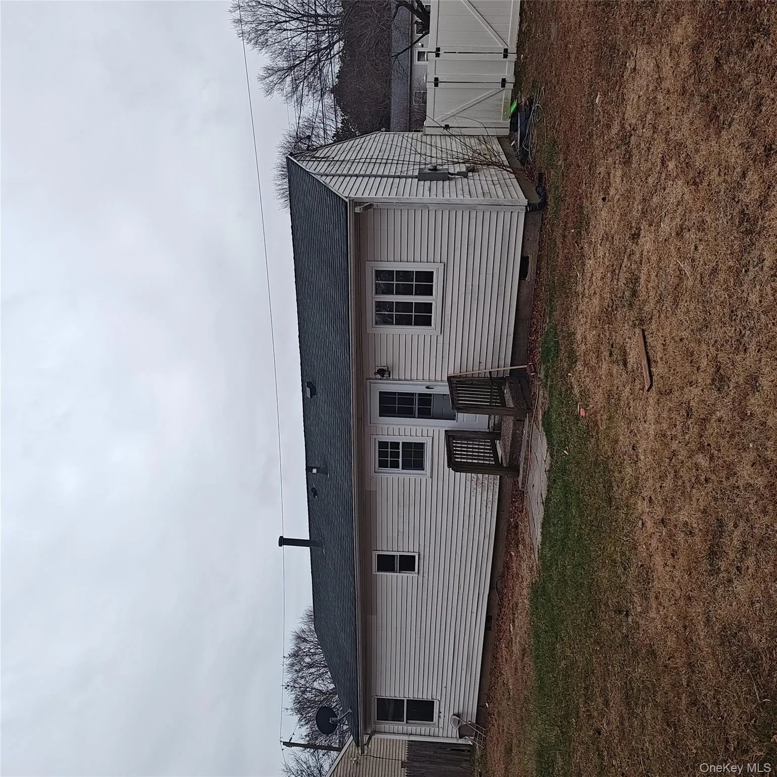 Rear view of house featuring crawl space, a shingled roof, a gate, and a patio Rear view of house featuring crawl space, a shingled roof, a gate, and a patio