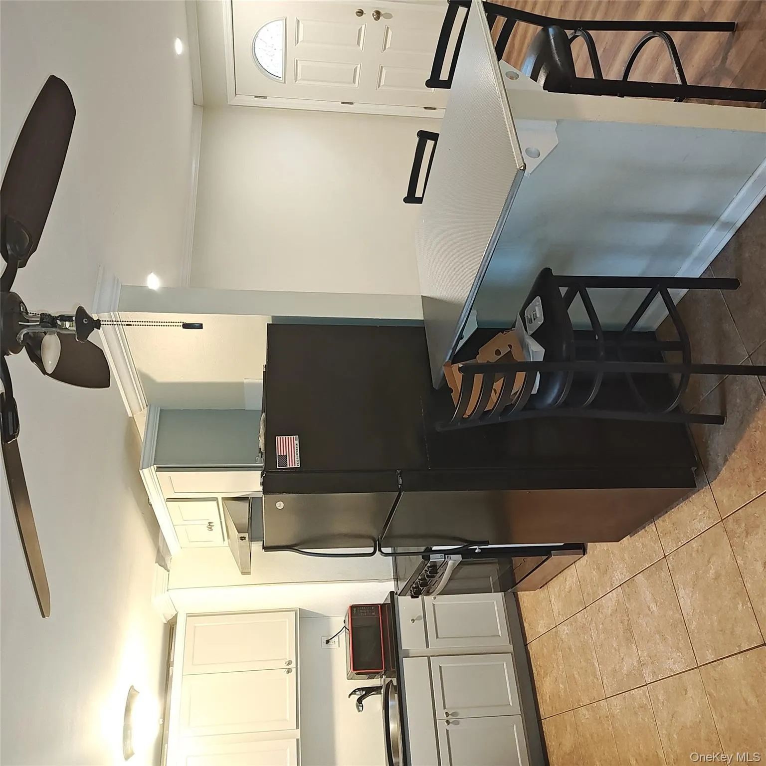 Kitchen with ceiling fan, a kitchen breakfast bar, dark countertops, freestanding refrigerator, and ornamental molding Kitchen with ceiling fan, a kitchen breakfast bar, dark countertops, freestanding refrigerator, and ornamental molding