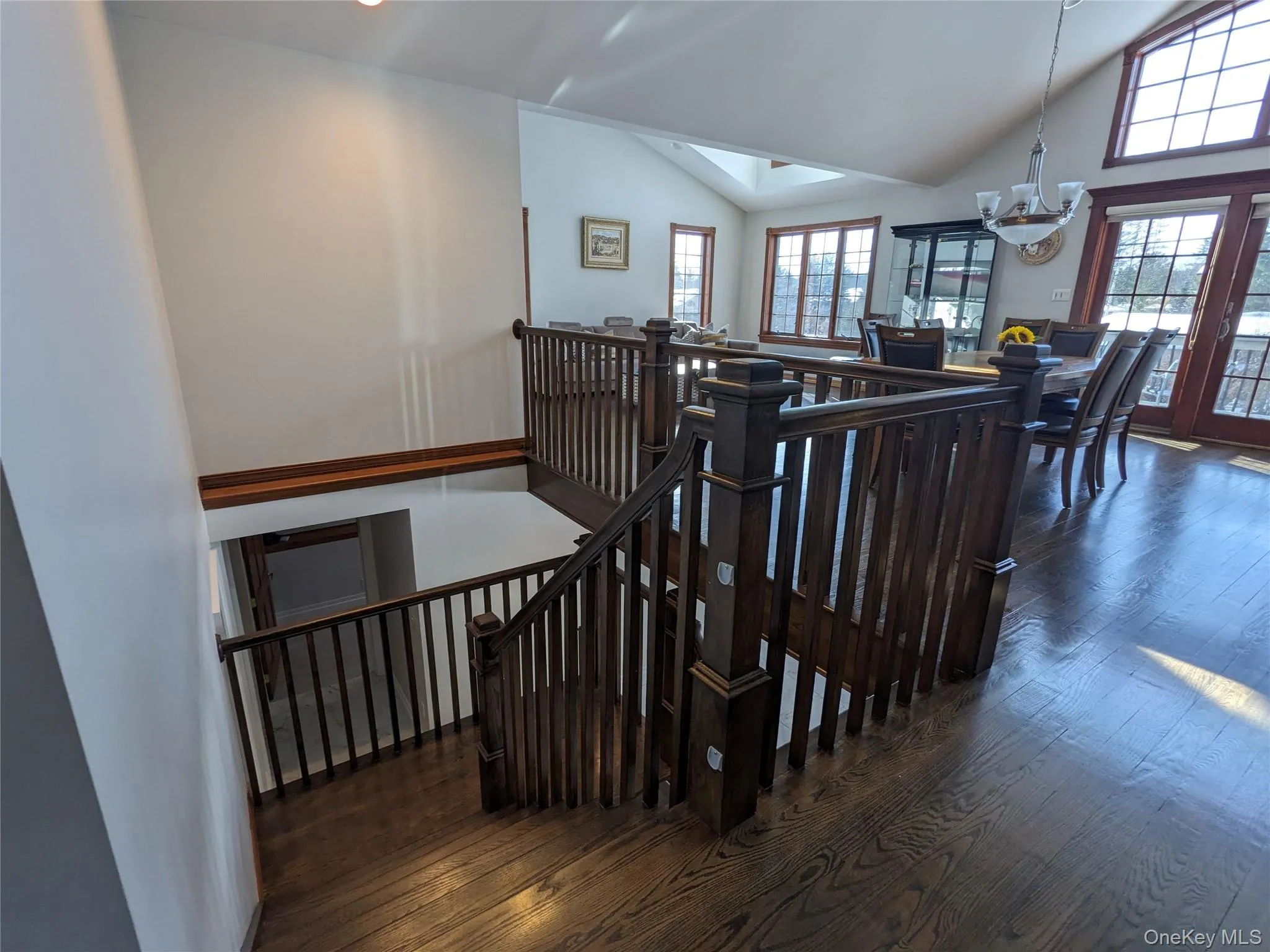 Staircase featuring hardwood / wood-style flooring, a chandelier, a skylight, and a towering ceiling Staircase featuring hardwood / wood-style flooring, a chandelier, a skylight, and a towering ceiling