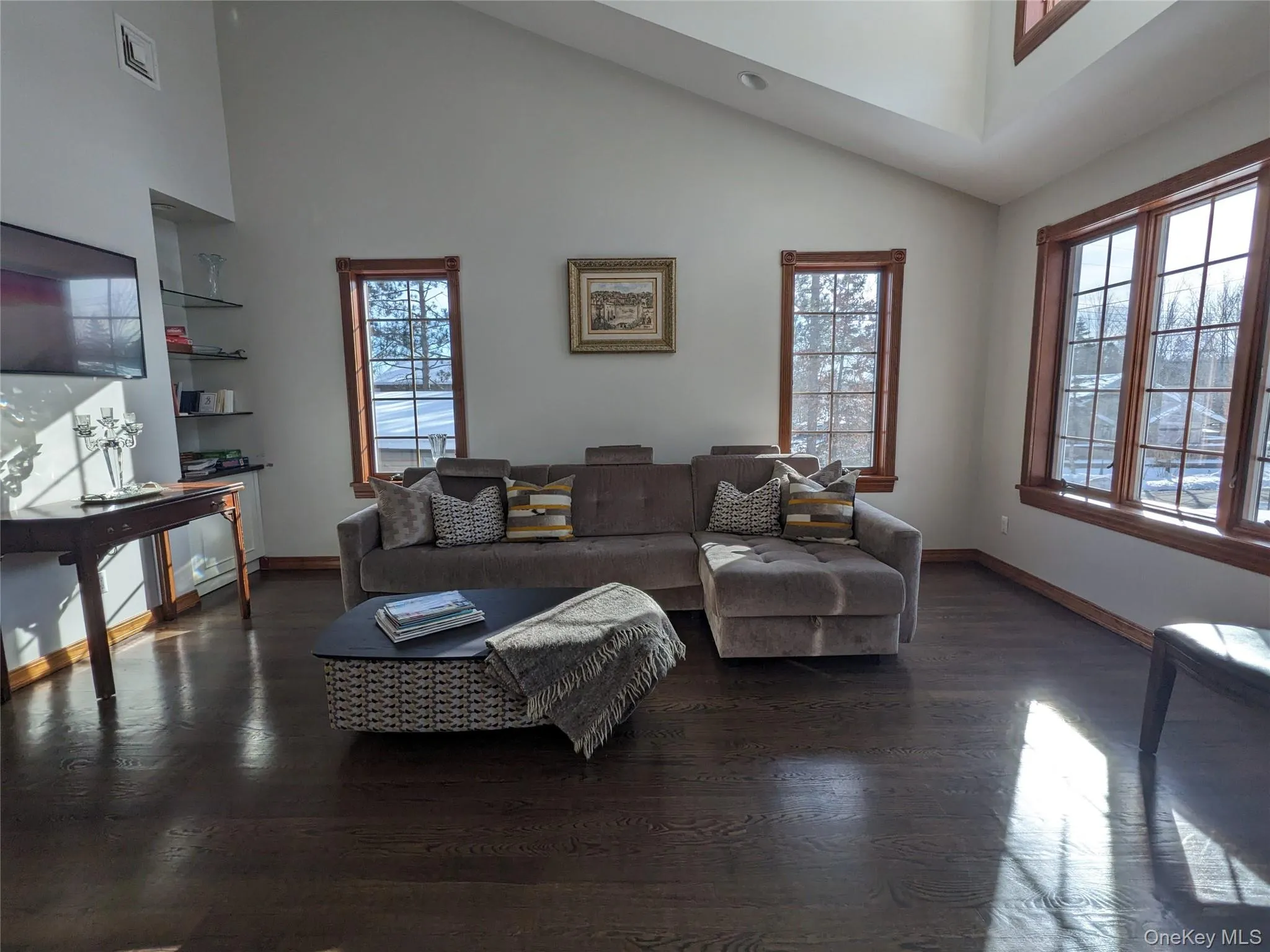 Living room featuring high vaulted ceiling and dark wood-style floors Living room featuring high vaulted ceiling and dark wood-style floors