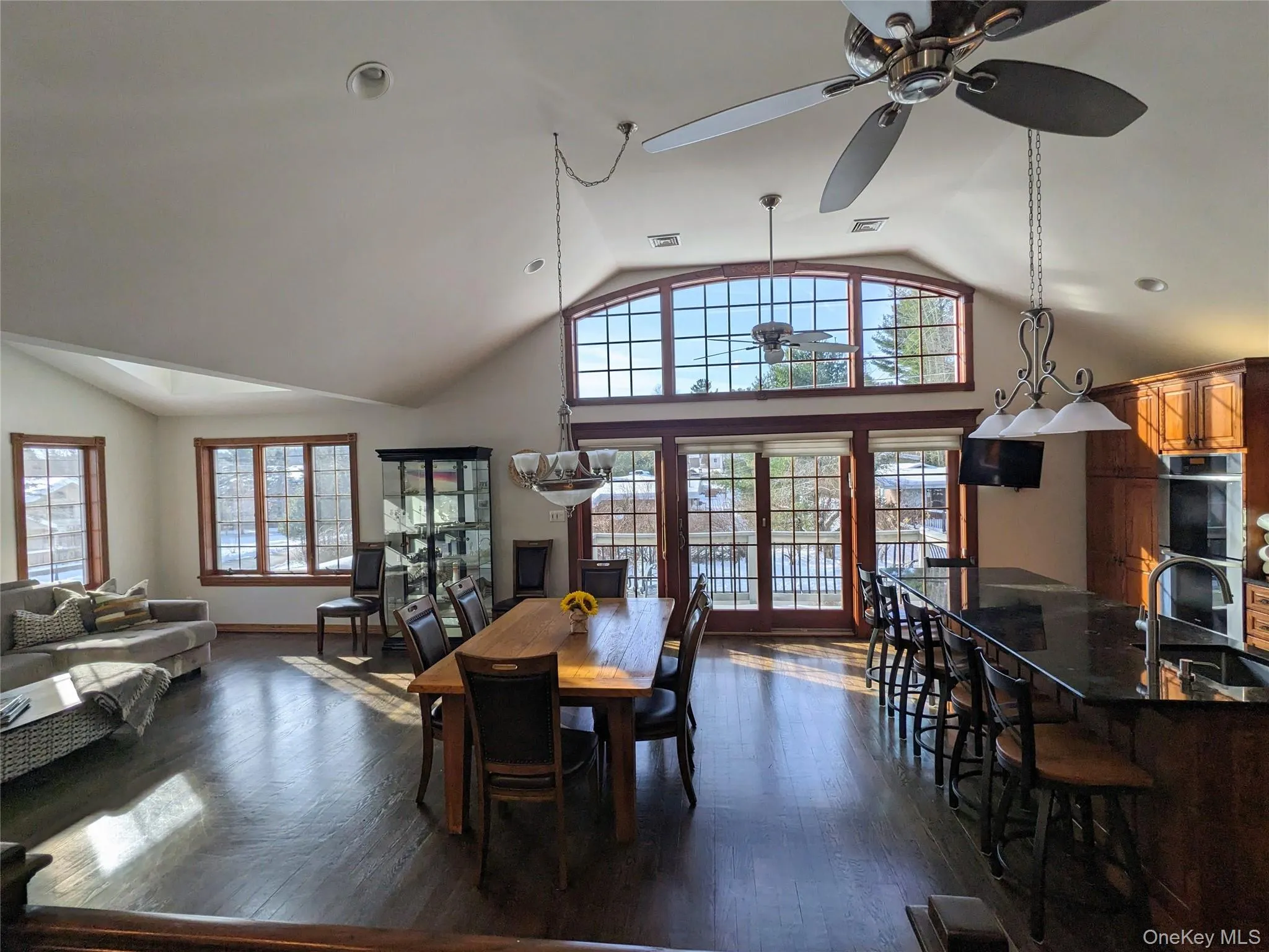 Dining space with healthy amount of natural light, dark wood-type flooring, high vaulted ceiling, and ceiling fan Dining space with healthy amount of natural light, dark wood-type flooring, high vaulted ceiling, and ceiling fan