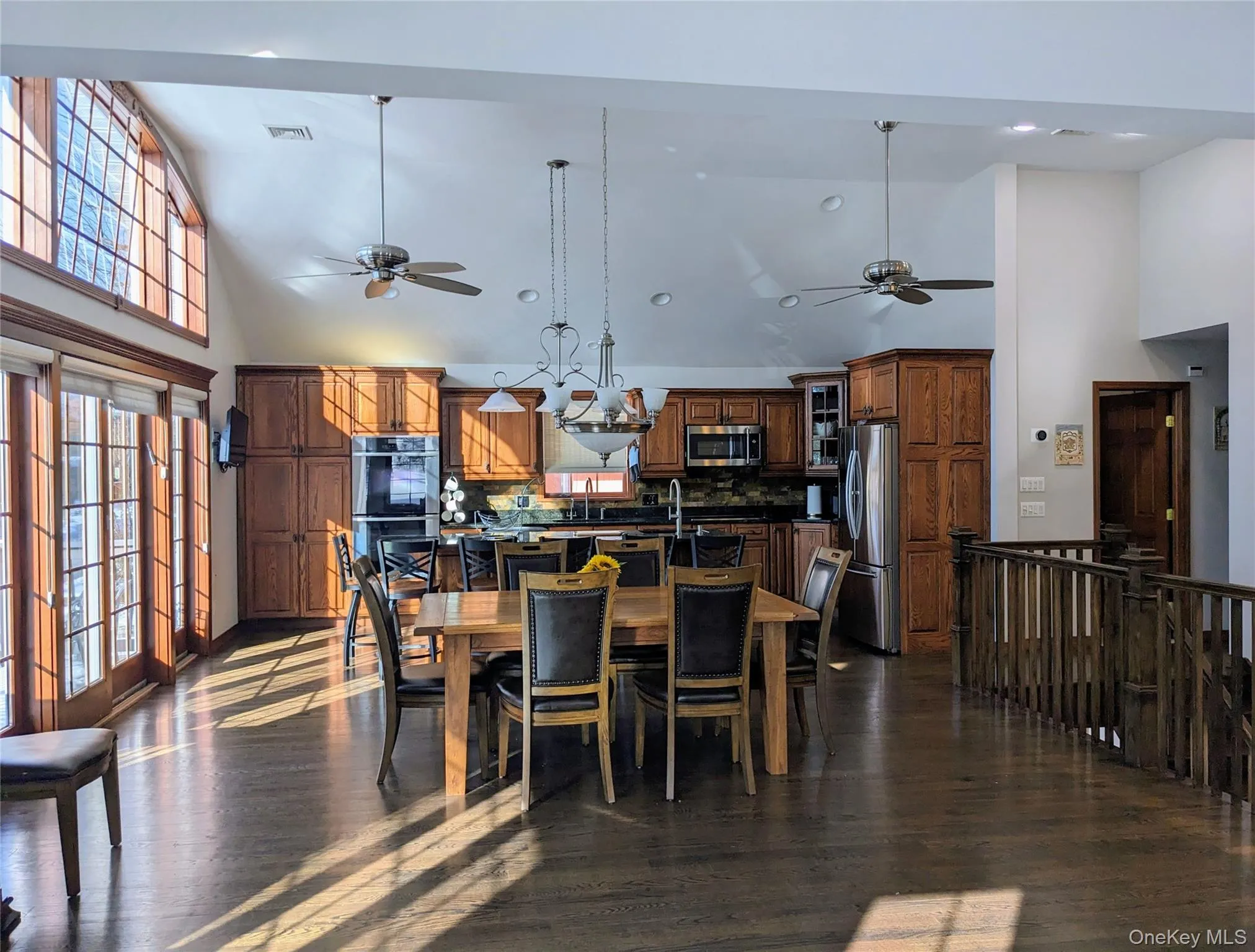 Dining space with high vaulted ceiling, a ceiling fan, and dark wood-style floors Dining space with high vaulted ceiling, a ceiling fan, and dark wood-style floors