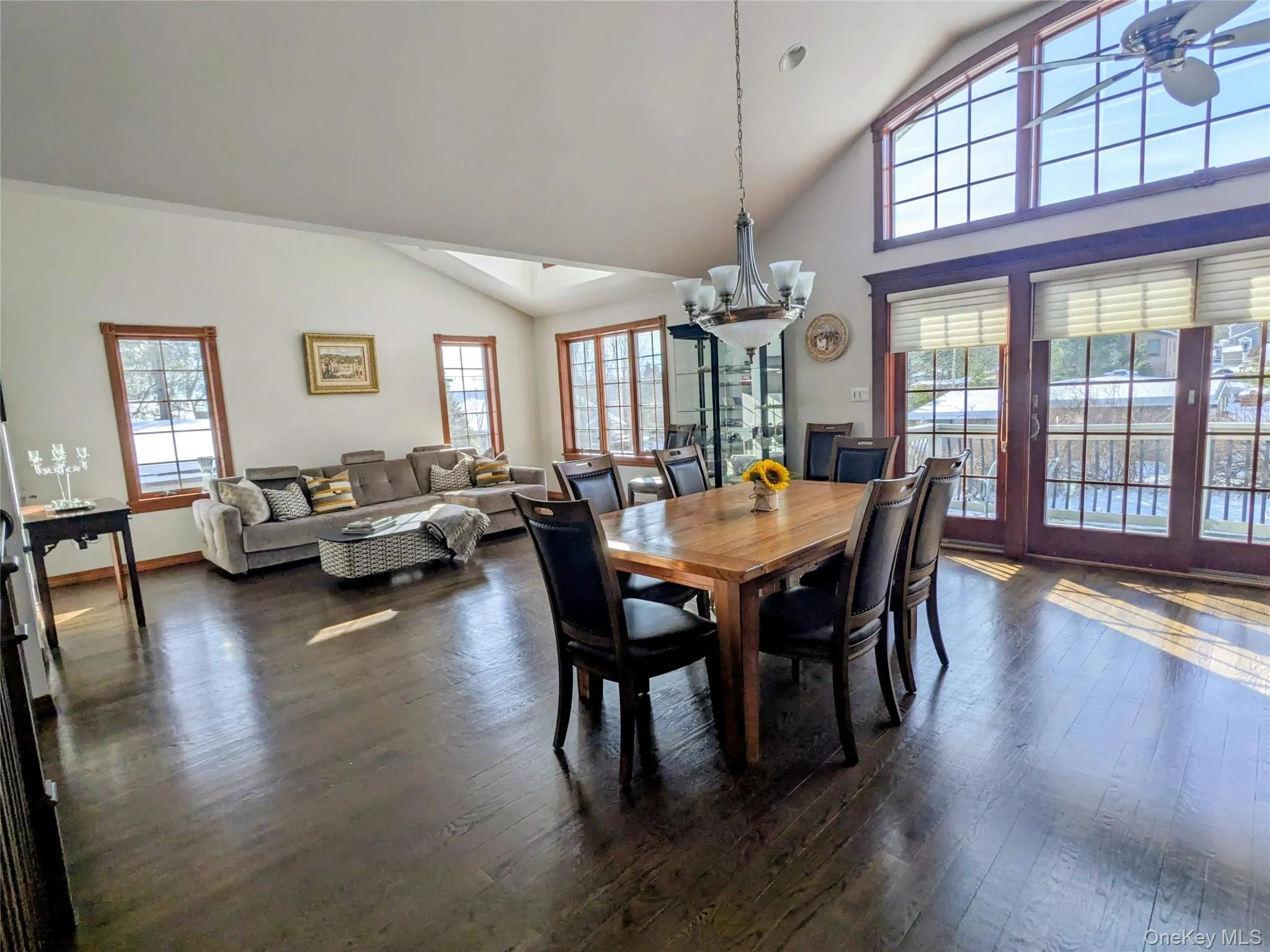 Dining room with a chandelier, plenty of natural light, dark wood-type flooring, and high vaulted ceiling Dining room with a chandelier, plenty of natural light, dark wood-type flooring, and high vaulted ceiling