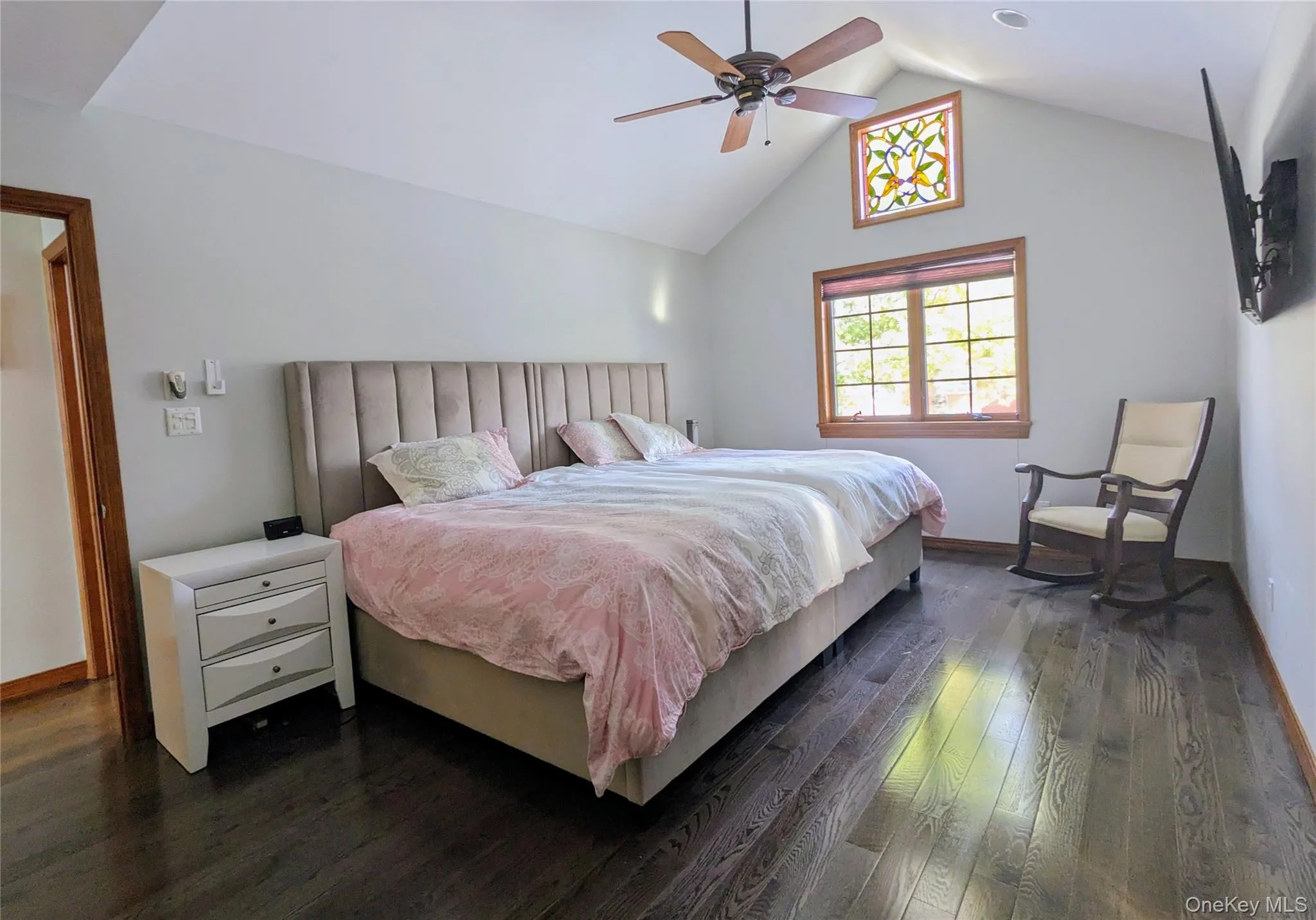 Bedroom featuring dark wood-style flooring, a ceiling fan, and high vaulted ceiling Bedroom featuring dark wood-style flooring, a ceiling fan, and high vaulted ceiling