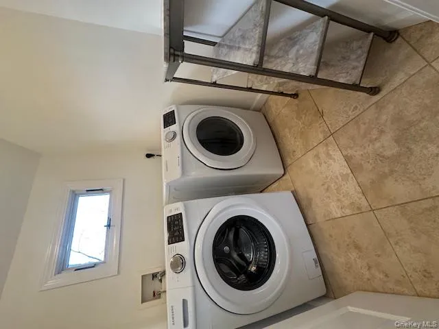Laundry room featuring washing machine and dryer, lofted ceiling, and light tile patterned flooring Laundry room featuring washing machine and dryer, lofted ceiling, and light tile patterned flooring