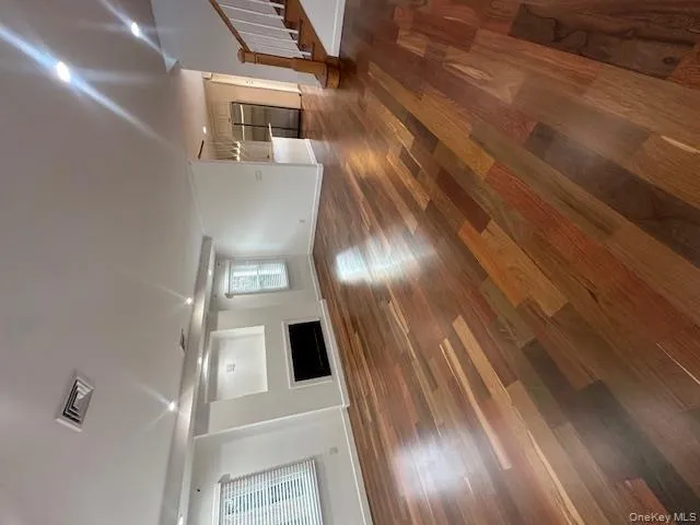 Unfurnished living room with stairs, dark wood-type flooring, a fireplace, and recessed lighting Unfurnished living room with stairs, dark wood-type flooring, a fireplace, and recessed lighting