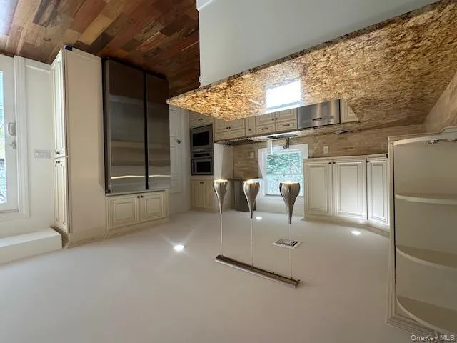 Kitchen featuring a peninsula, stainless steel appliances, light stone counters, open shelves, and recessed lighting Kitchen featuring a peninsula, stainless steel appliances, light stone counters, open shelves, and recessed lighting