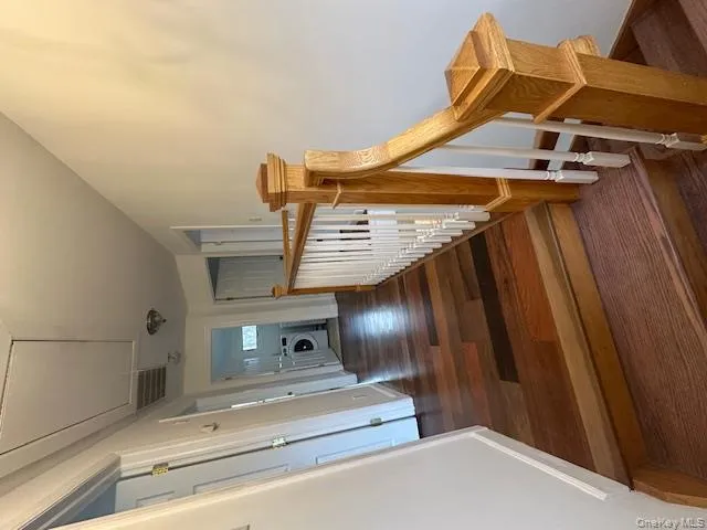 Corridor with attic access, dark wood-style floors, washer / clothes dryer, and an upstairs landing Corridor with attic access, dark wood-style floors, washer / clothes dryer, and an upstairs landing
