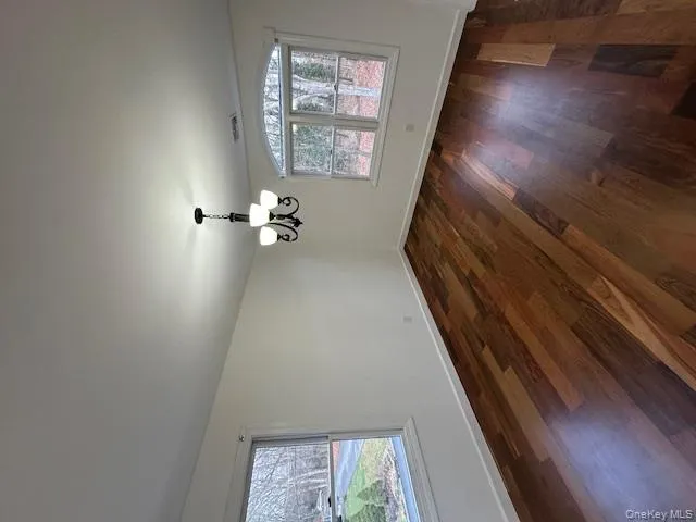 Spare room featuring dark wood finished floors and a chandelier Spare room featuring dark wood finished floors and a chandelier