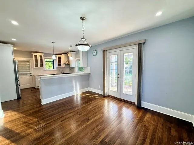 Kitchen with recessed lighting, glass insert cabinets, french doors, a peninsula, and decorative light fixtures Kitchen with recessed lighting, glass insert cabinets, french doors, a peninsula, and decorative light fixtures