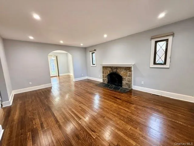 Unfurnished living room featuring arched walkways, a fireplace, dark wood-style flooring, and recessed lighting Unfurnished living room featuring arched walkways, a fireplace, dark wood-style flooring, and recessed lighting