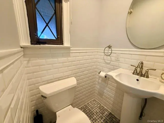 Half bathroom with wainscoting and tile walls Half bathroom with wainscoting and tile walls