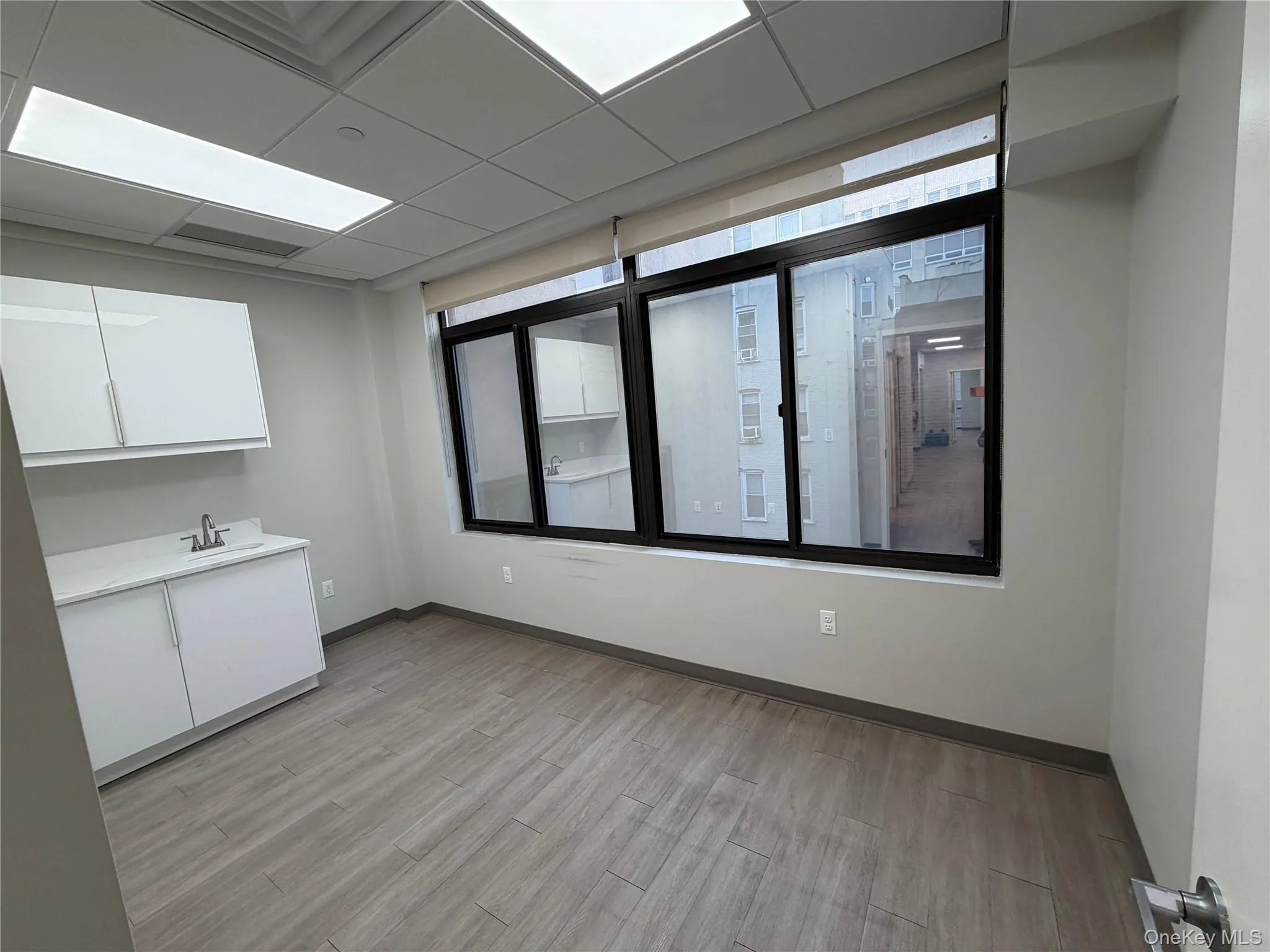 Unfurnished room featuring a drop ceiling and light wood-style flooring Unfurnished room featuring a drop ceiling and light wood-style flooring