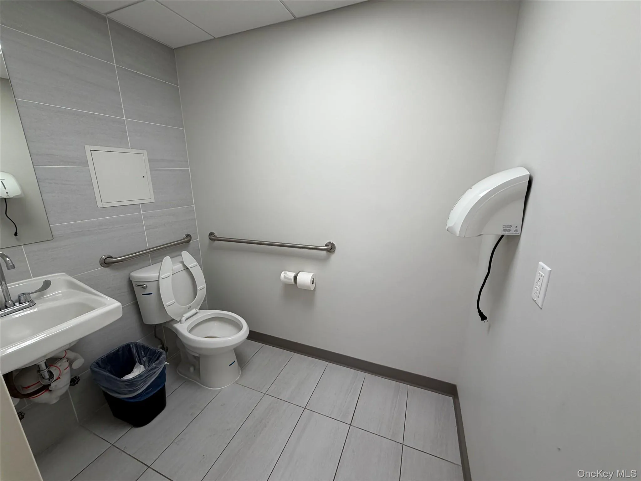 Bathroom featuring tile walls and light tile patterned flooring Bathroom featuring tile walls and light tile patterned flooring