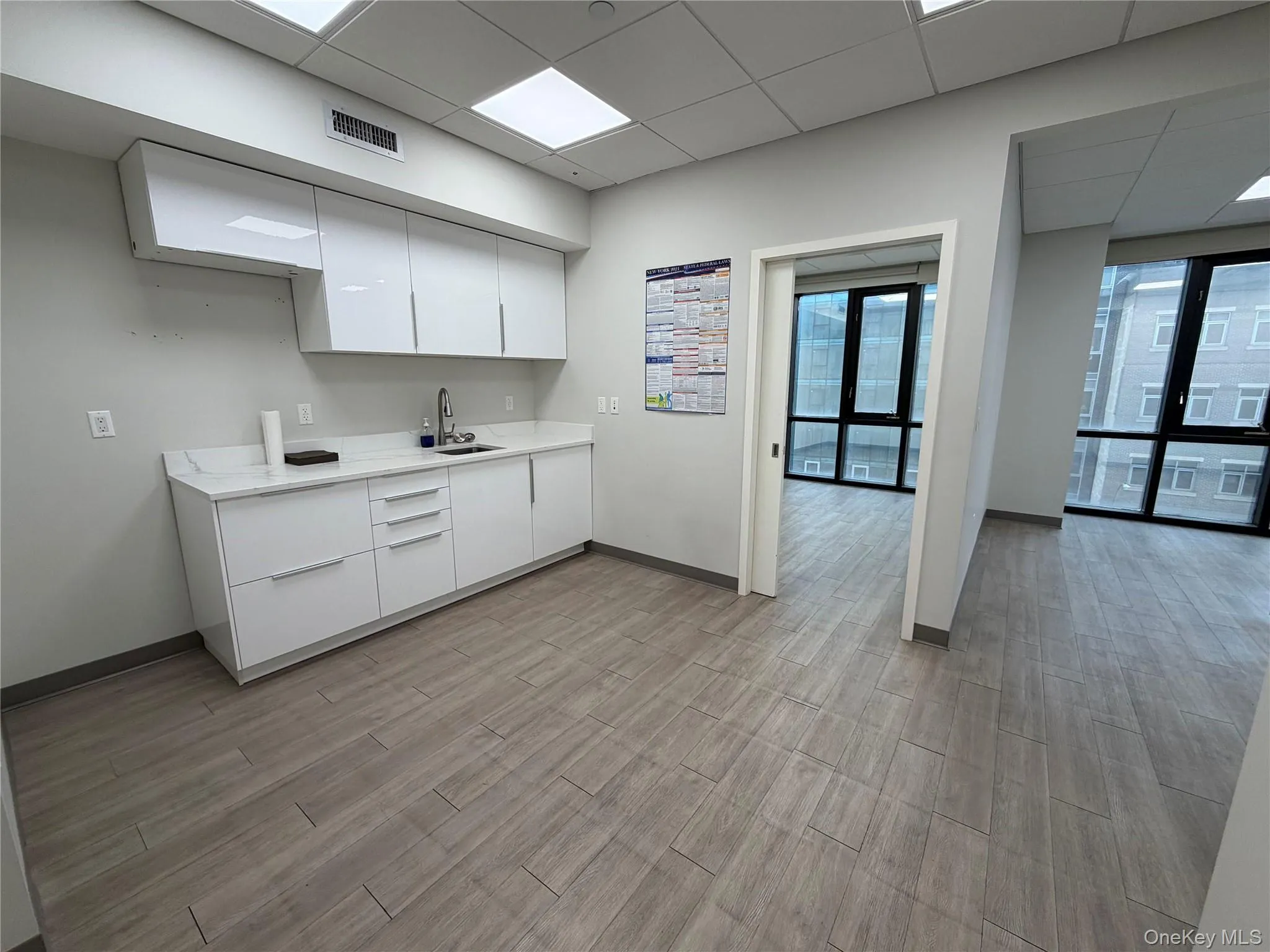 Kitchen with modern cabinets, white cabinetry, a paneled ceiling, and wood tiled floors Kitchen with modern cabinets, white cabinetry, a paneled ceiling, and wood tiled floors